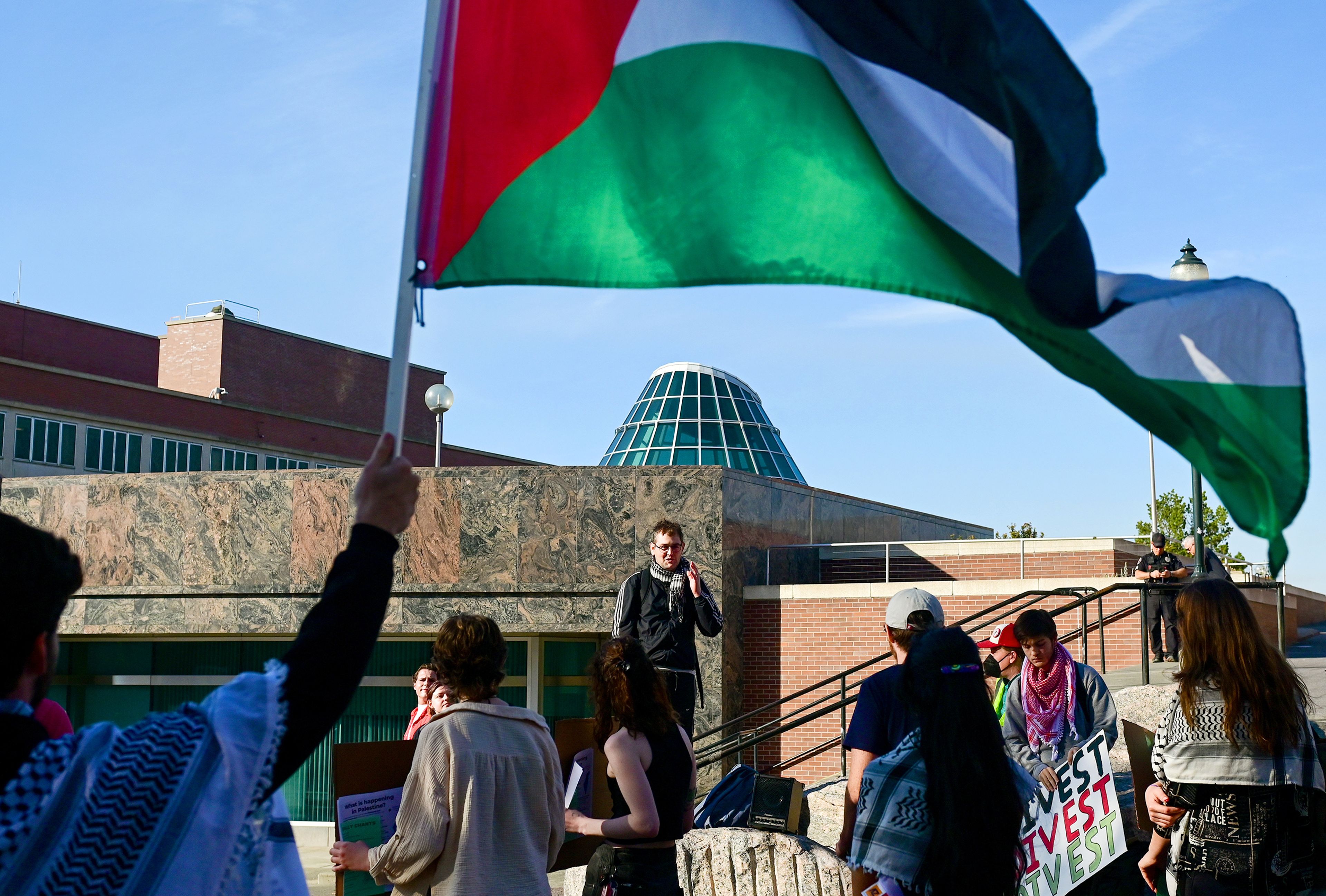 A Palestinian flag ripples in the wind as Pat Mahoney, center, speaks to a group gathered Monday afternoon for a Pullman for Palestine rally on Washington State University campus Monday in Pullman. The group marched to downtown and attended a listening session for a drafted ceasefire resolution.