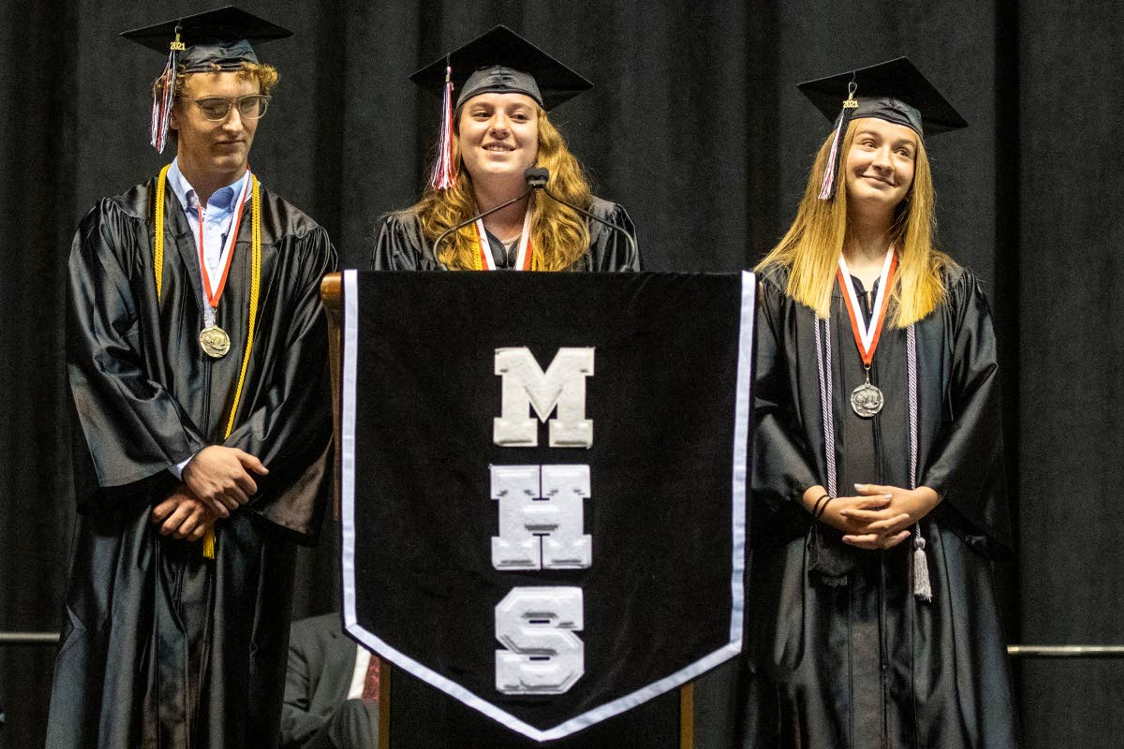 Graduates Lane Hanson, from left, Laurel Hicke and Ava Jakich-Kunze speak to Moscow High School’s Class of 2021 during their graduation commencement at the University of Idaho’s Kibbie Dome on Friday night.