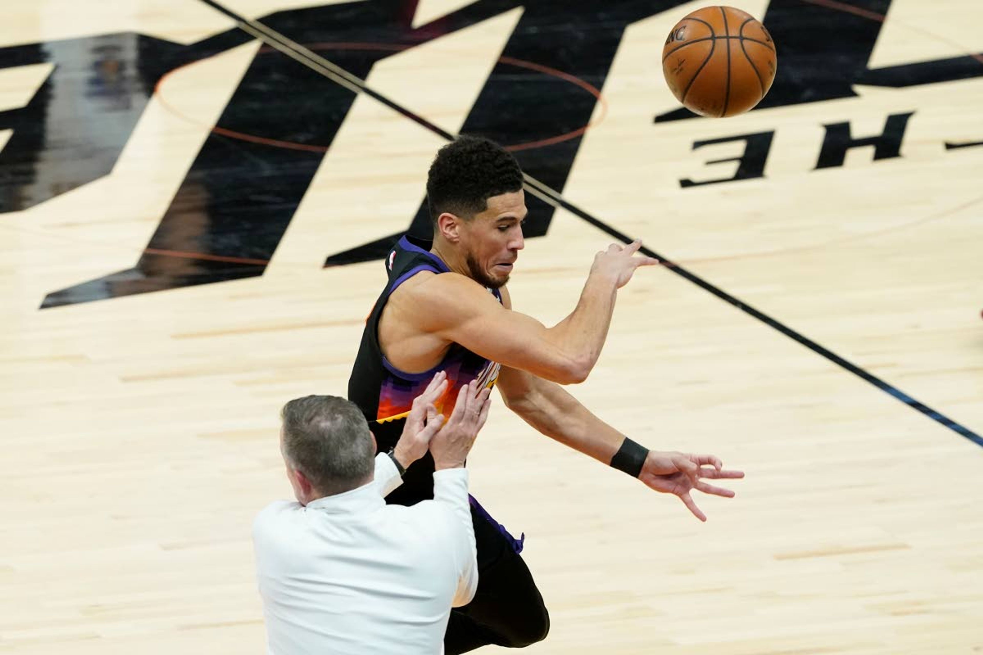 Phoenix Suns guard Devin Booker tries to save a loose ball as he collides with Denver Nuggets head coach Michael Malone during the second half of Game 2 of an NBA basketball second-round playoff series, Wednesday, June 9, 2021, in Phoenix. (AP Photo/Matt York)