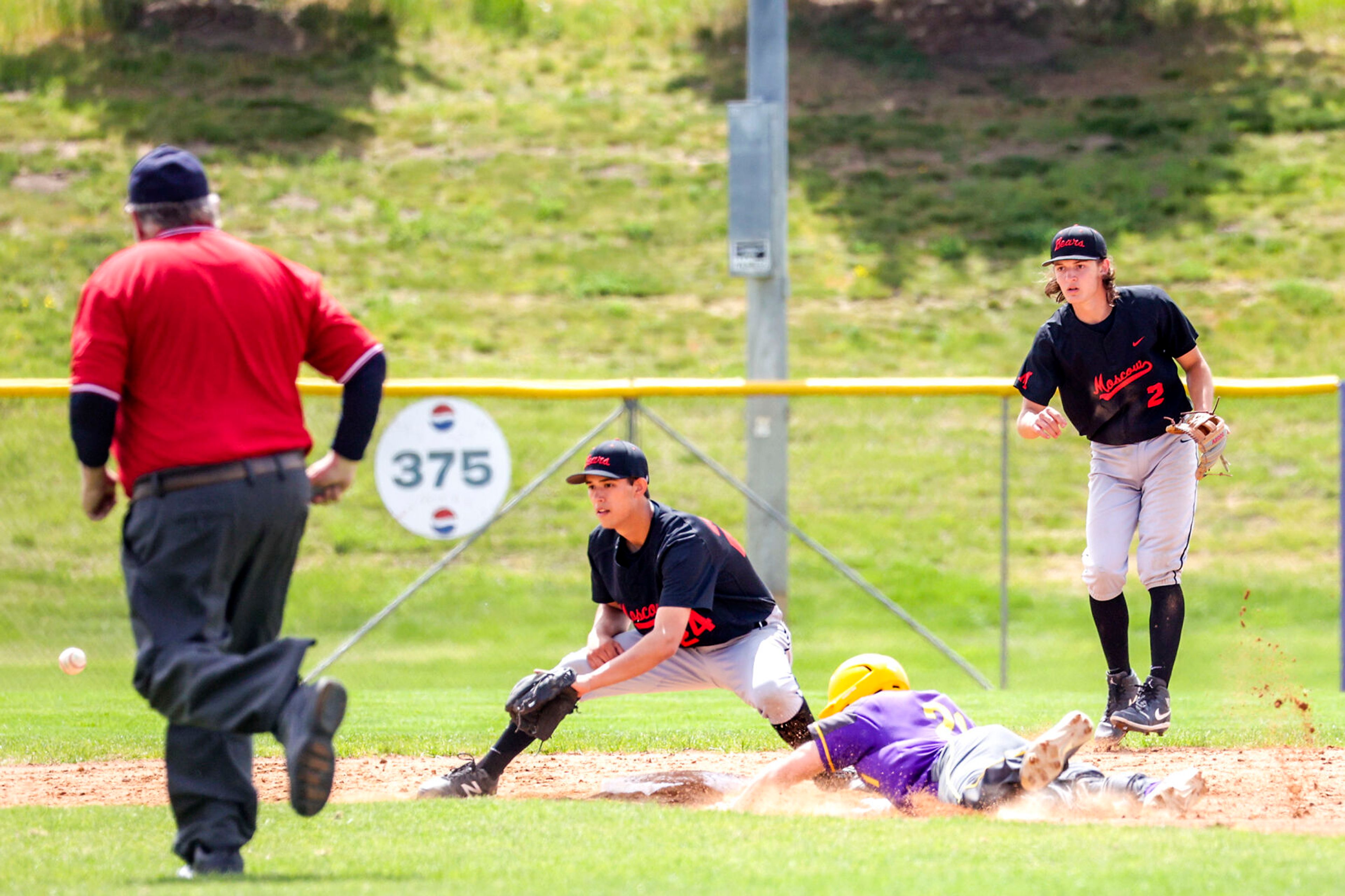 Lewiston’s Cruz Hepburn dives towards second base, safe on a steal attempt, as Moscow’s Isaac Staszkow waits for the throw from catcher Jack Bales at Church Field on Saturday. Moscow's Mike Kiblen backs up the play. Lewiston defeated Moscow 6-4.