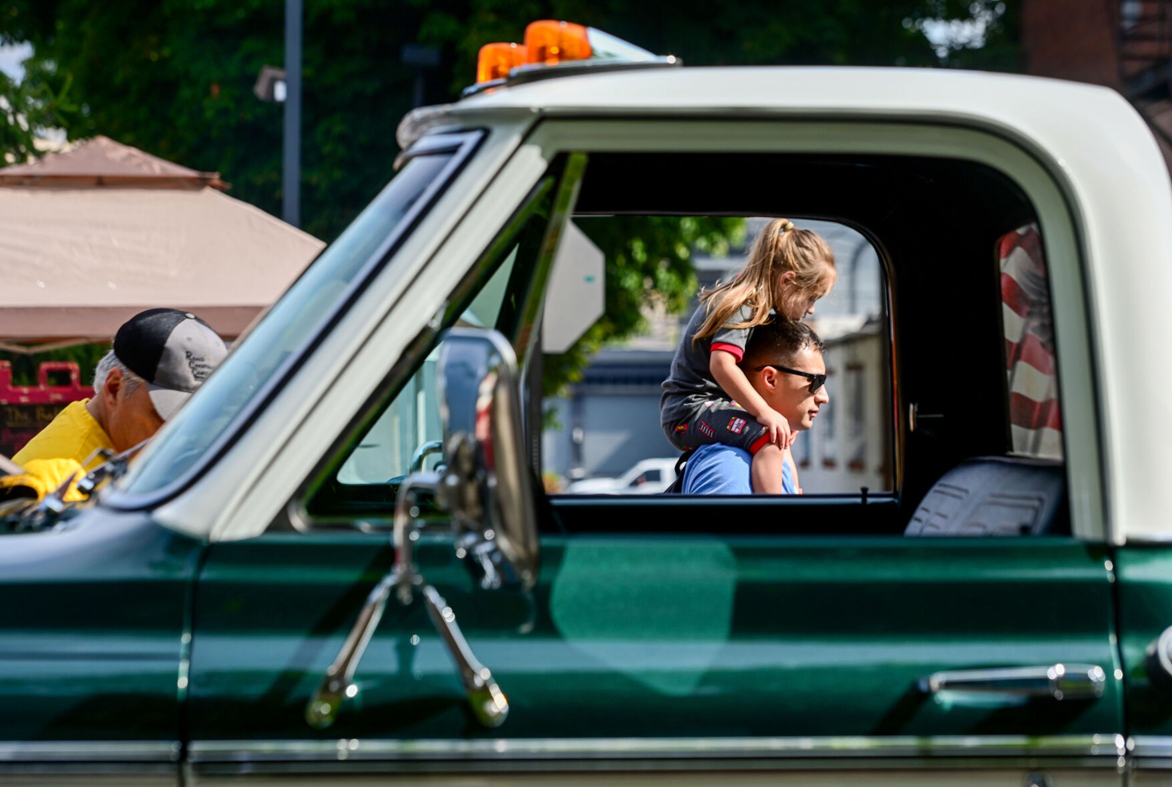 Families walk along Main Street on Saturday in Lewiston, passing through the open window-view of a 1972 Chevrolet K10 on display as part of the Lewiston Hot August Nights on Saturday.