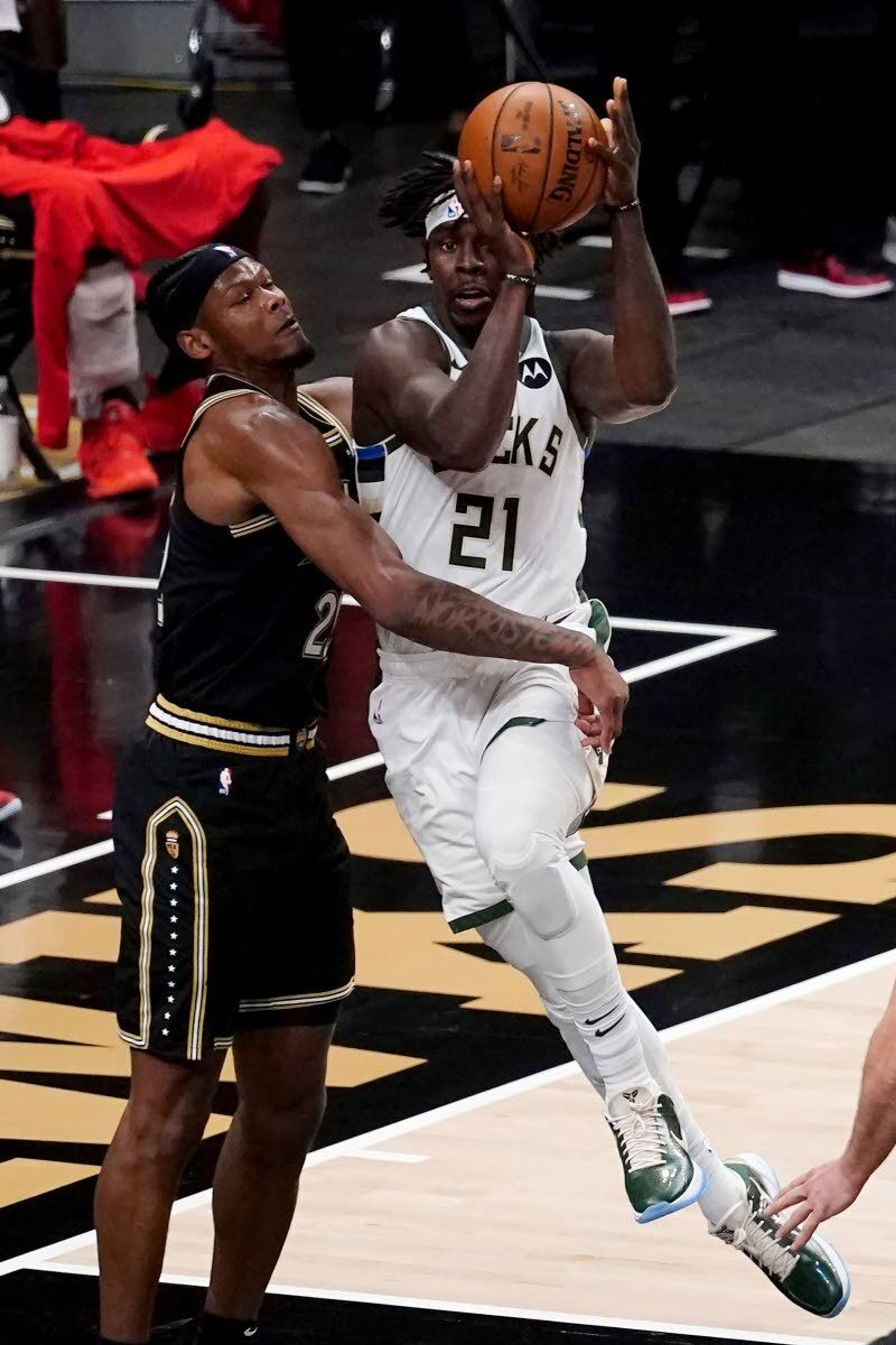 Milwaukee Bucks guard Jrue Holiday (21) drives against Atlanta Hawks forward Cam Reddish (22) during the first half of Game 6 of the Eastern Conference finals in the NBA basketball playoffs Saturday, July 3, 2021, in Atlanta. (AP Photo/John Bazemore)