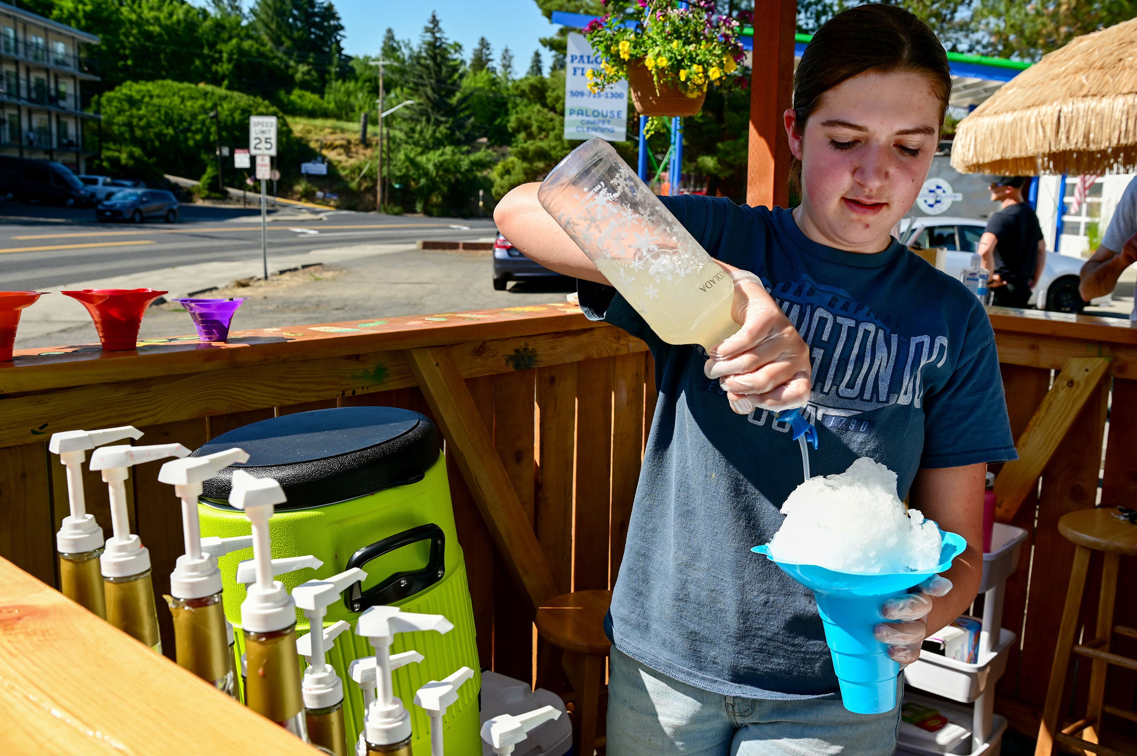 Manager Addyson Fitzgerald tops a shaved ice with pina colada syrup at the Shiver Shack in Pullman on Tuesday.