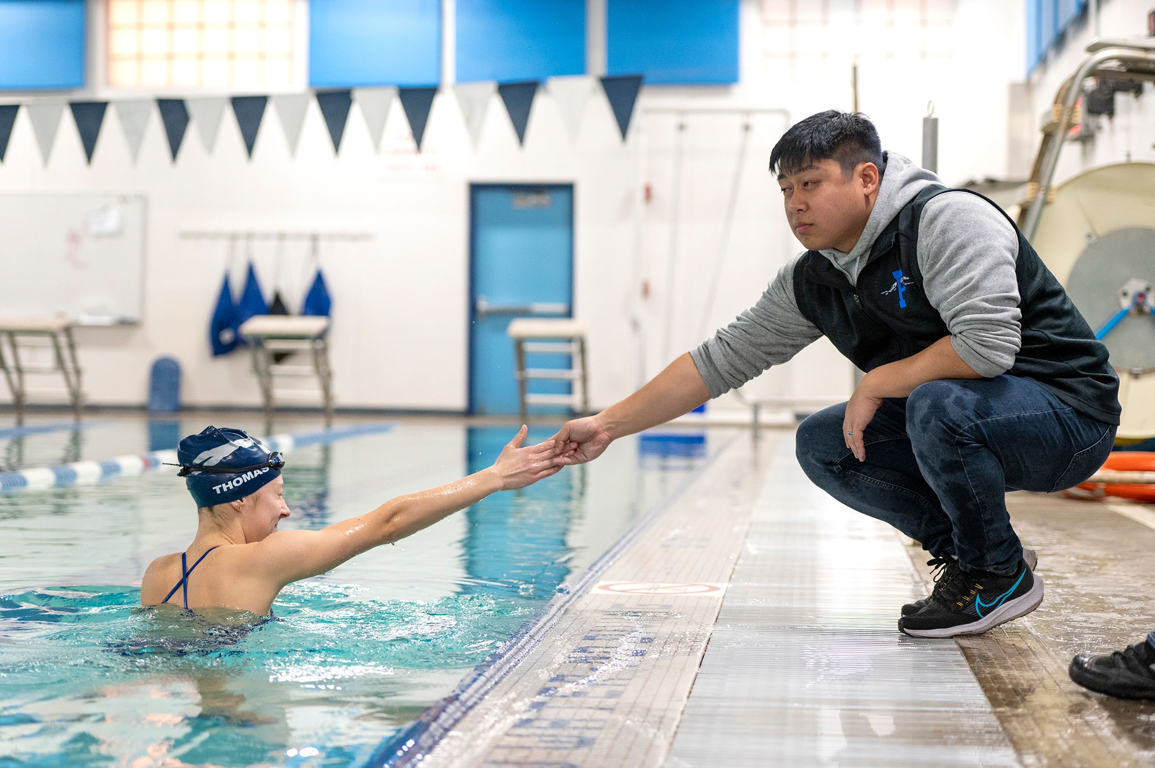 Pullman’s Codi Thomas shakes hands with coach Eric Chung during practice Wednesday at the Pullman Aquatic Center in preparation for the Washington high school state swim meet.