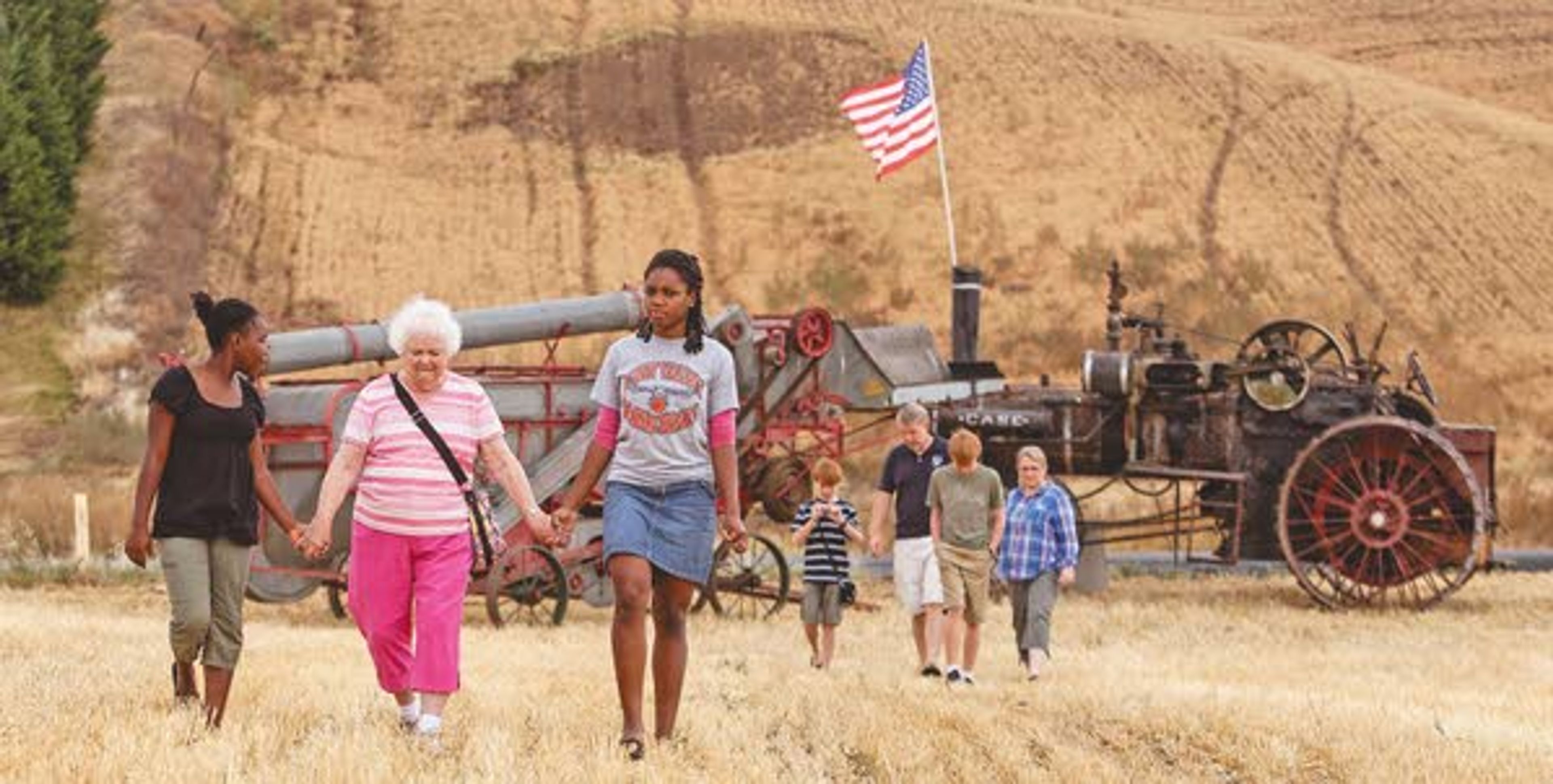 Shirly Ensley, center, of Colfax, holds hands with Rachelle Arnold, left, 16, and her sister, Rose, 18, both of Spokane, as they walk away from a threshing machine on display Monday during the rained-out annual Palouse Empire Threshing Bee outside the Palouse Empire Fairgrounds near Colfax.