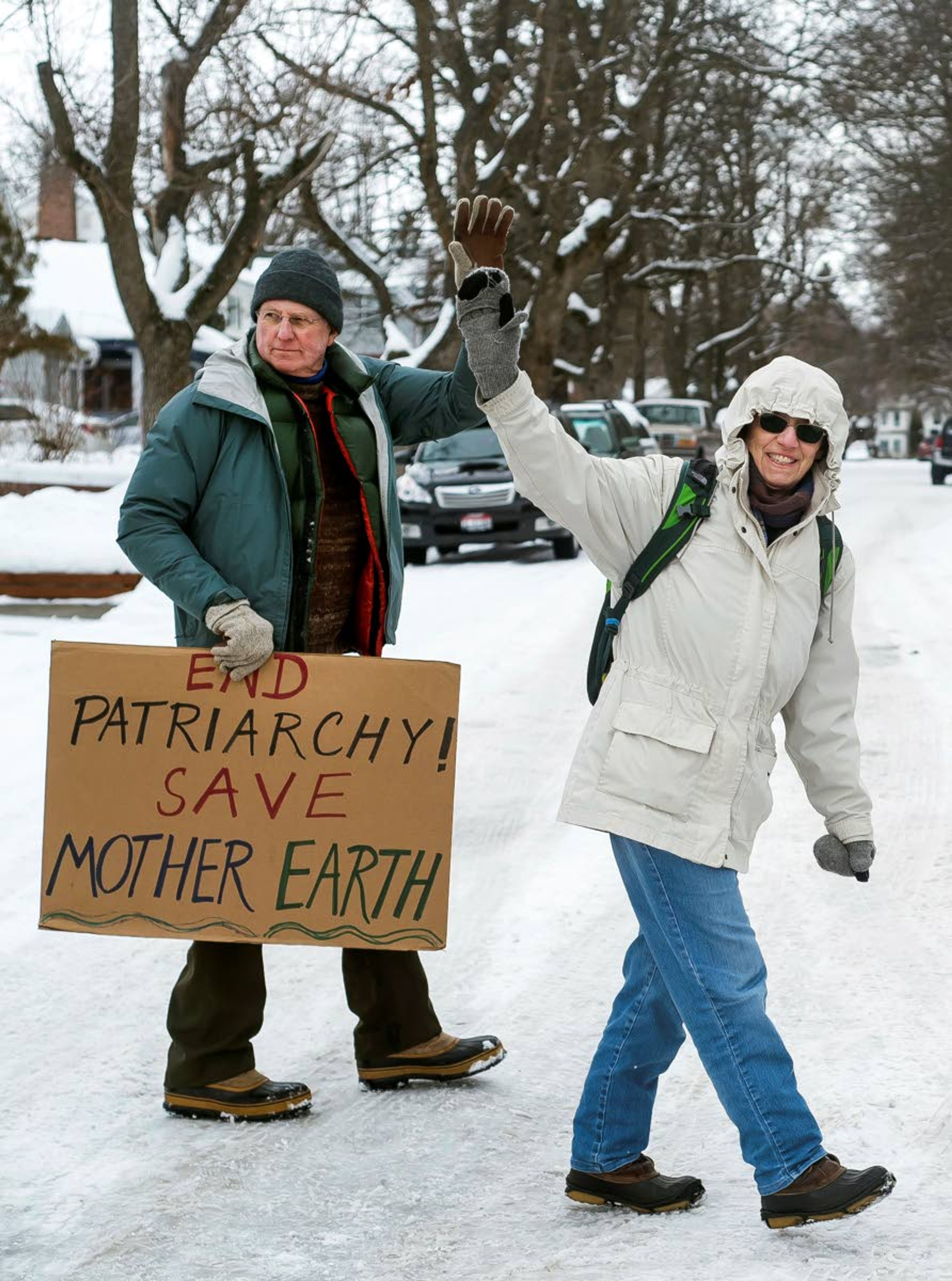 Bill Beck, of Moscow, (left) and Claudine Zender, of Moscow, (right) wave to a car honking in support during the 2020 Women's March on the Palouse in Moscow on Saturday.