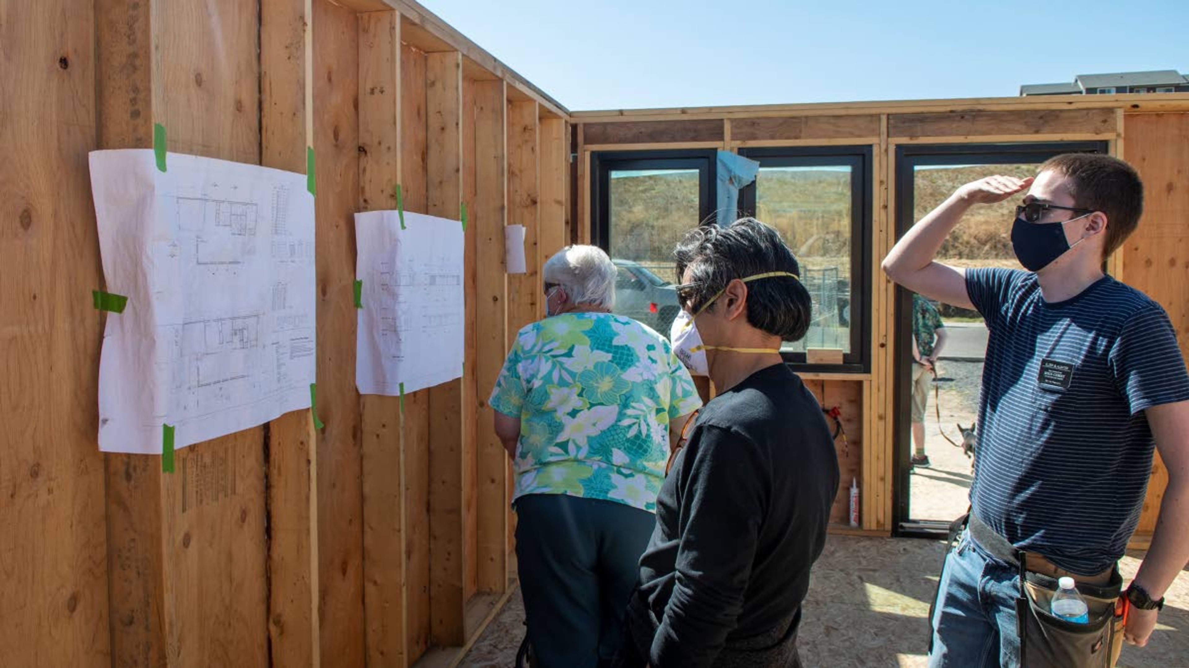 Connie Hall, from left, Taiji Miyasaka and Elder Slaughter observe outlines of the energy efficient home during a celebration of raising the final wall in Uniontown on Thursday afternoon.