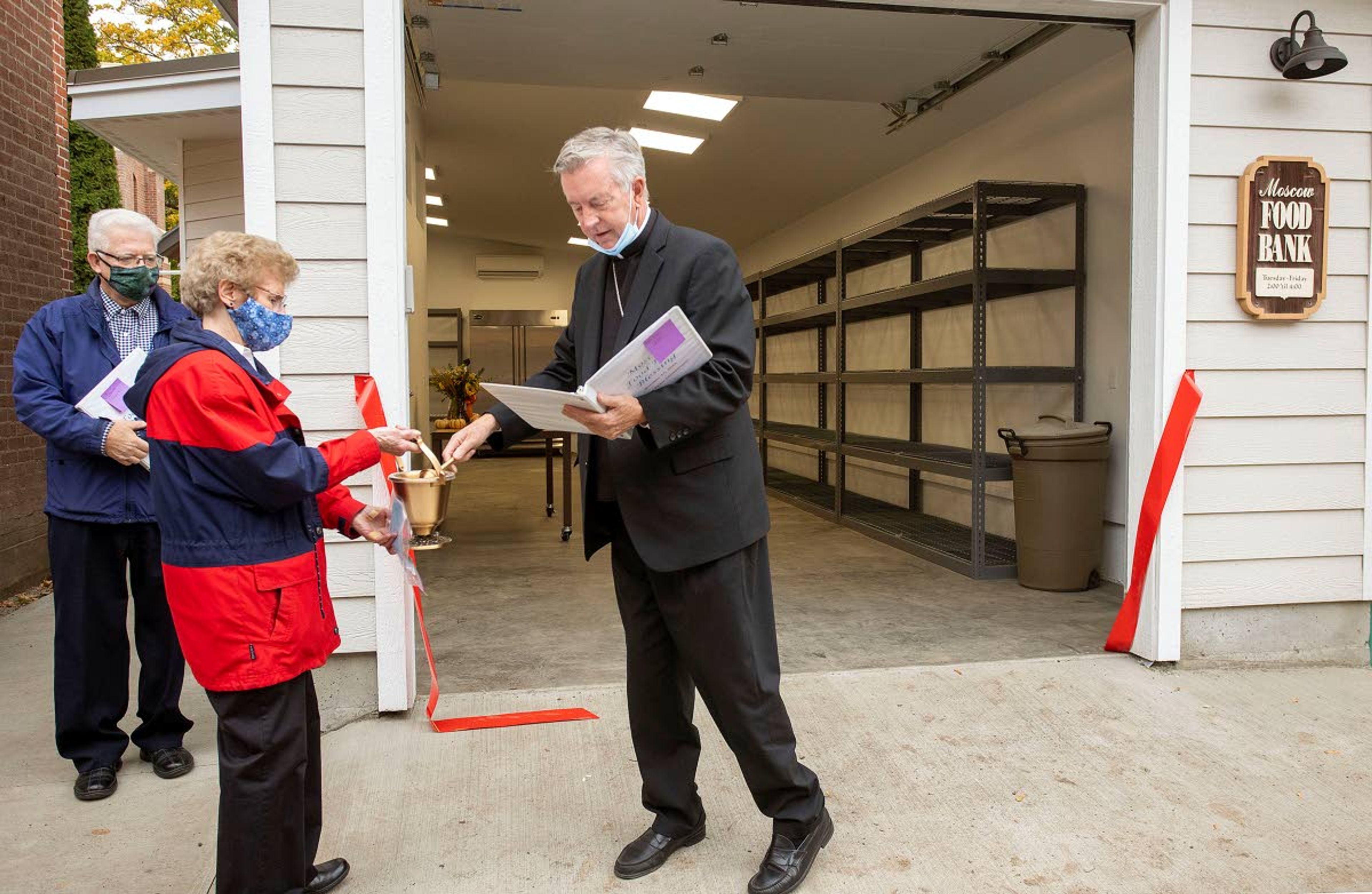 Bishop Peter Christensen of the Roman Catholic Diocese of Boise, right, sprinkles holy water on the new distribution and storage building at the Moscow Food Bank while blessing it on Saturday. The new building adds 740-square-feet of space to the food bank.