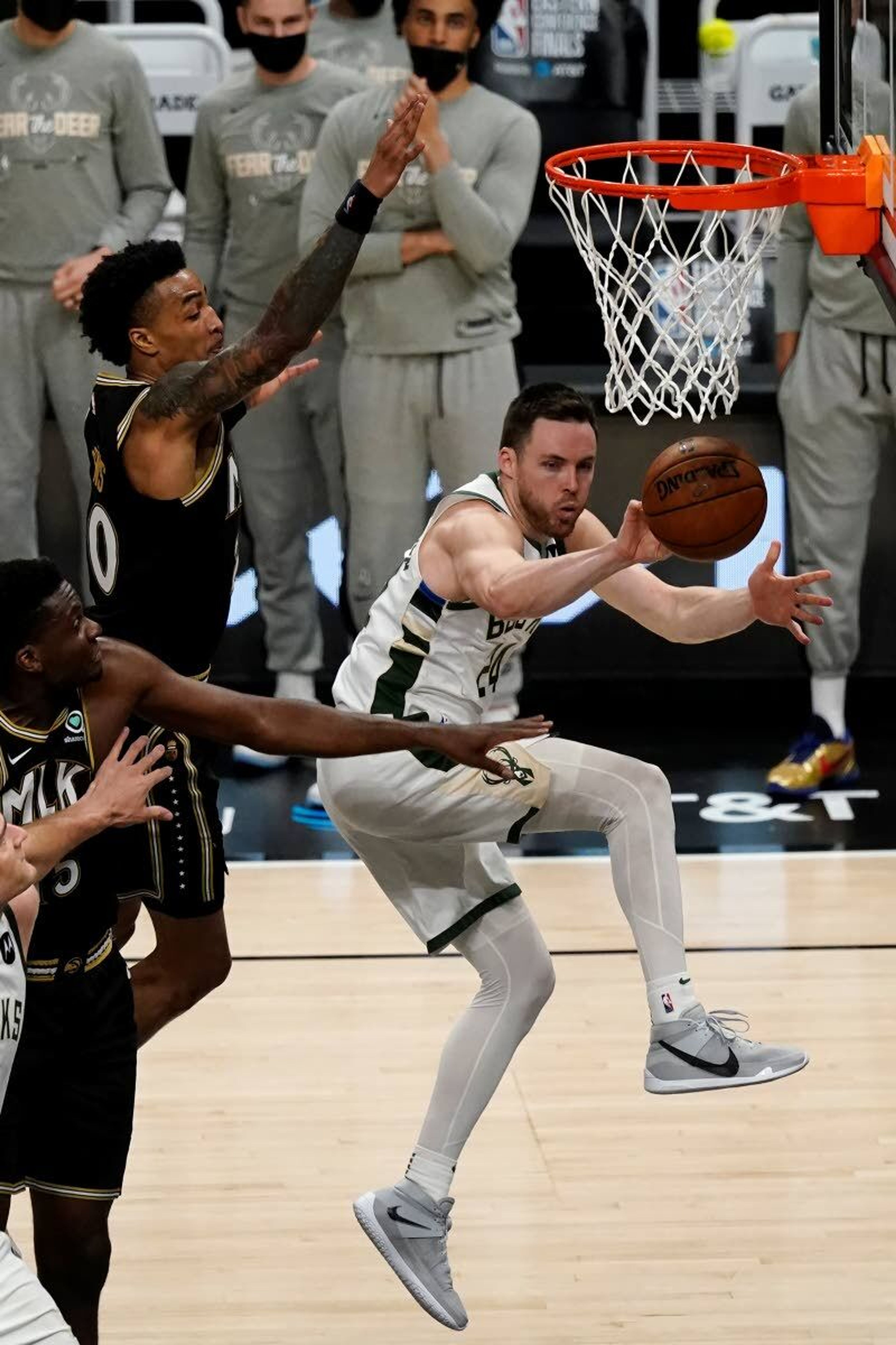 Milwaukee Bucks guard Pat Connaughton (24) passes the ball as Atlanta Hawks John Collins (20) and Clint Capella (15) defend during the second half in Game 6 of the Eastern Conference finals in the NBA basketball playoffs Saturday, July 3, 2021, in Atlanta. (AP Photo/John Bazemore)