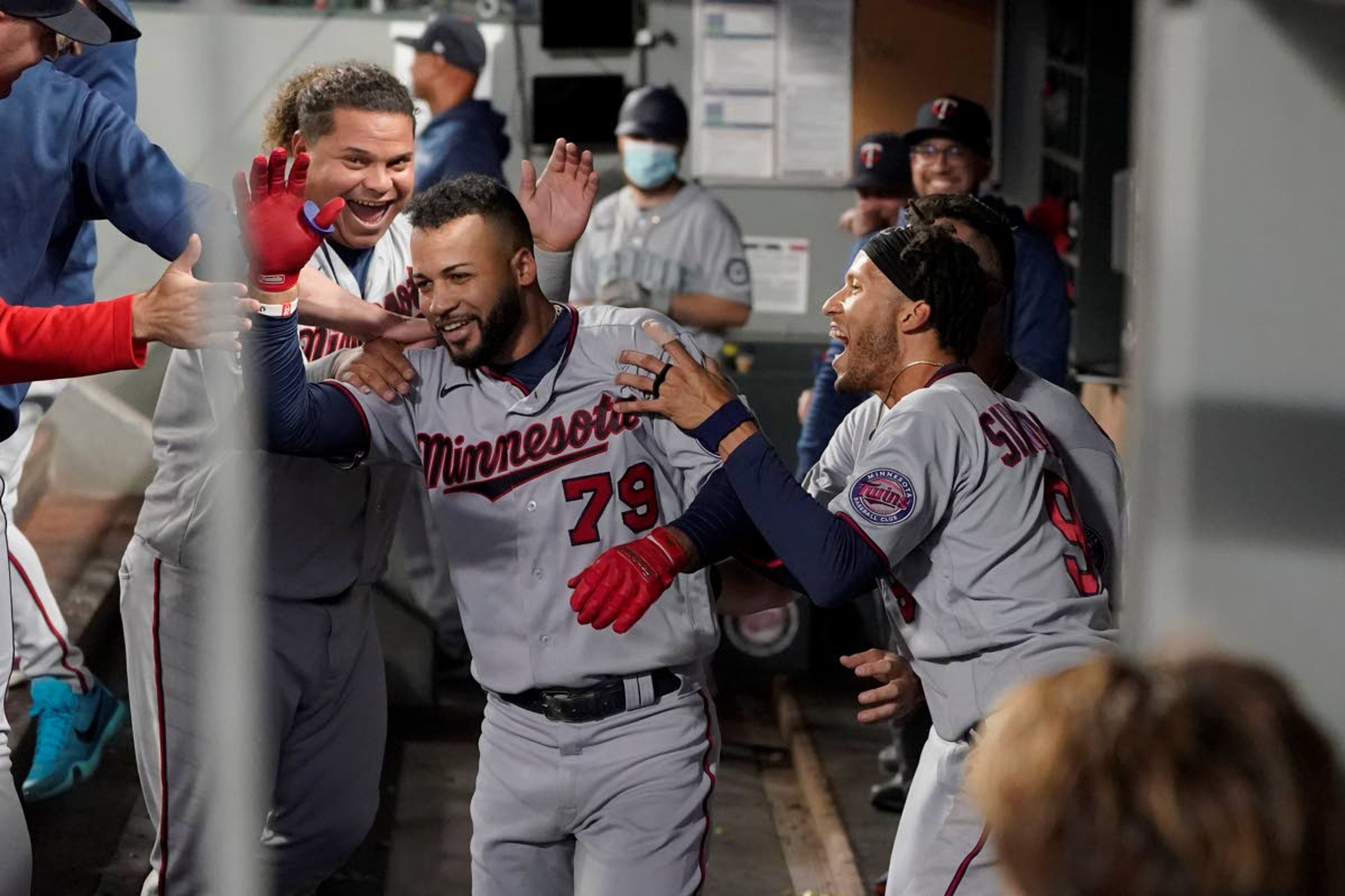 Minnesota Twins' Gilberto Celestino (79) is greeted by teammates Willians Astudillo, left, and Andrelton Simmons, right, after Celestino, who made his major-league debut on June 2, 2021, hit his first MLB career home run during the fourth inning of a baseball game against the Seattle Mariners, Monday, June 14, 2021, in Seattle. His teammates pretended to ignore the rookie until he reached the very end of the dugout and then moved in for the traditional run-scoring congratulations. (AP Photo/Ted S. Warren)