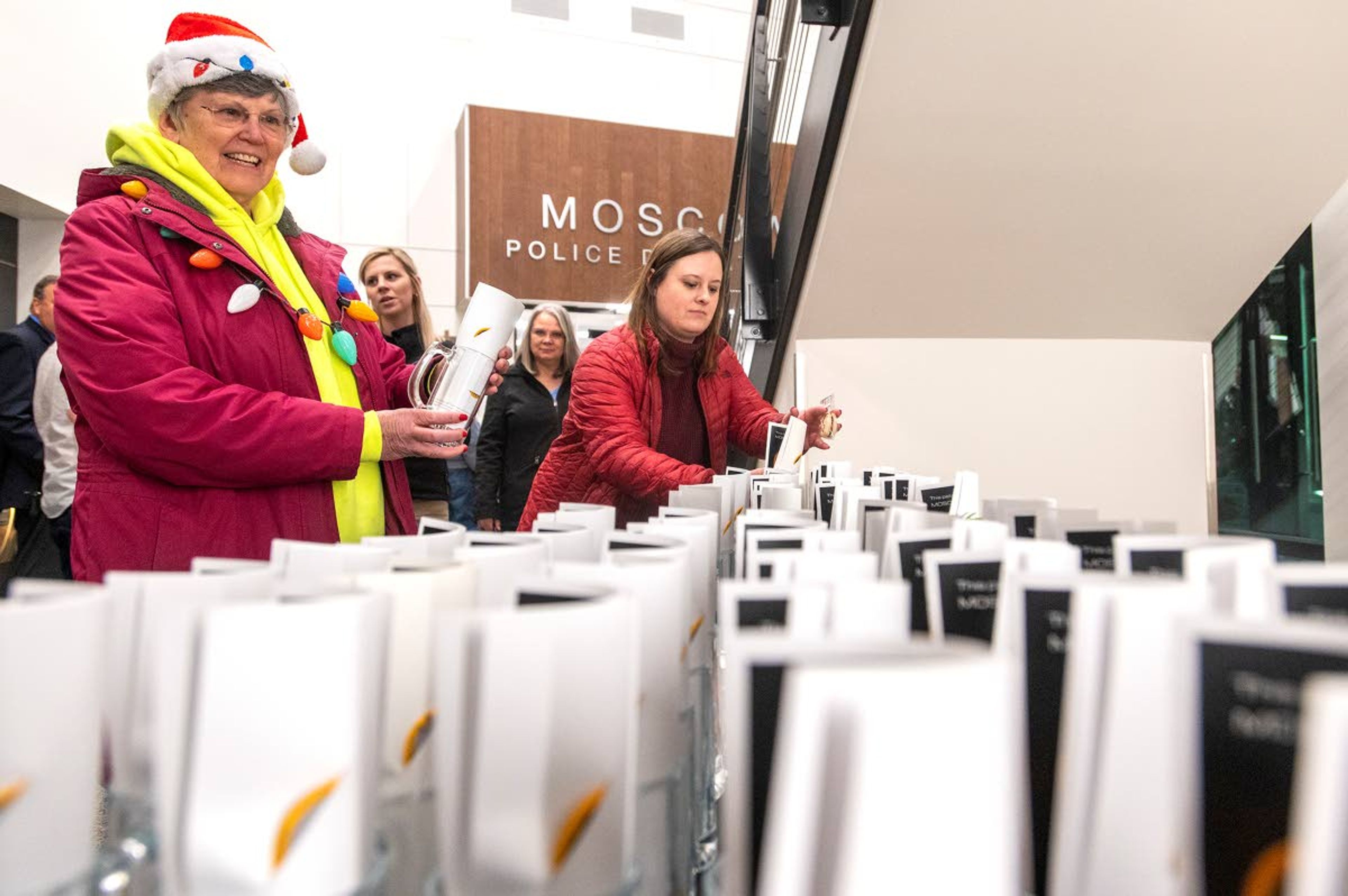 Sue Scott, left, observes a table filled with gifts for those attending a tour Moscow Police Department’s new station. The gift table consists of glass mugs containing a retired patch that was worn by Moscow police officers.