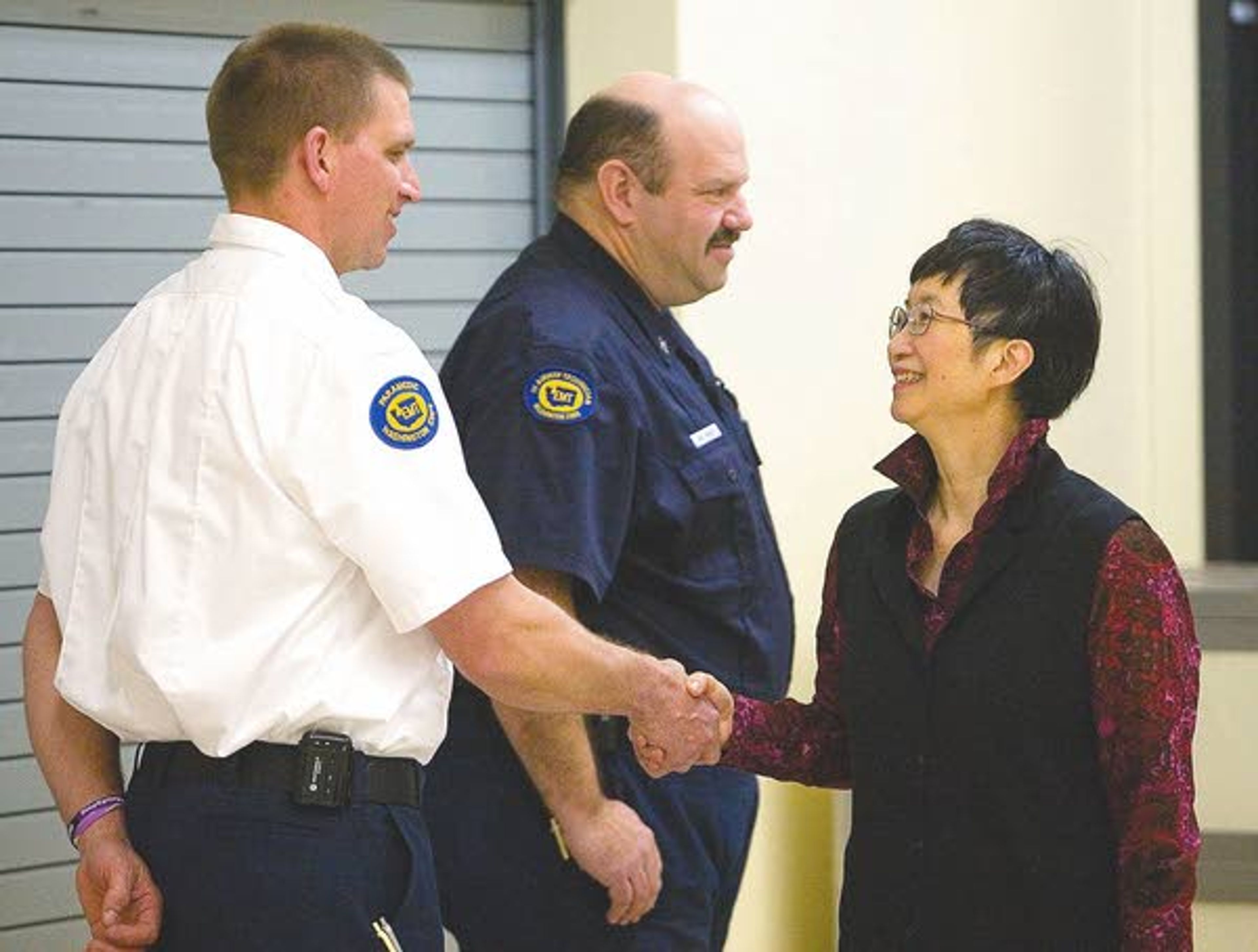 Special education paraprofessional Lina Quock, right, thanks Pullman firefighters Ryan Scharnhorst, left, and Eric Reiber after an assembly at Franklin Elementary School on Tuesday. The firefighters were part of a five-man crew that responded when Quock had a heart attack at the school on Dec. 17.