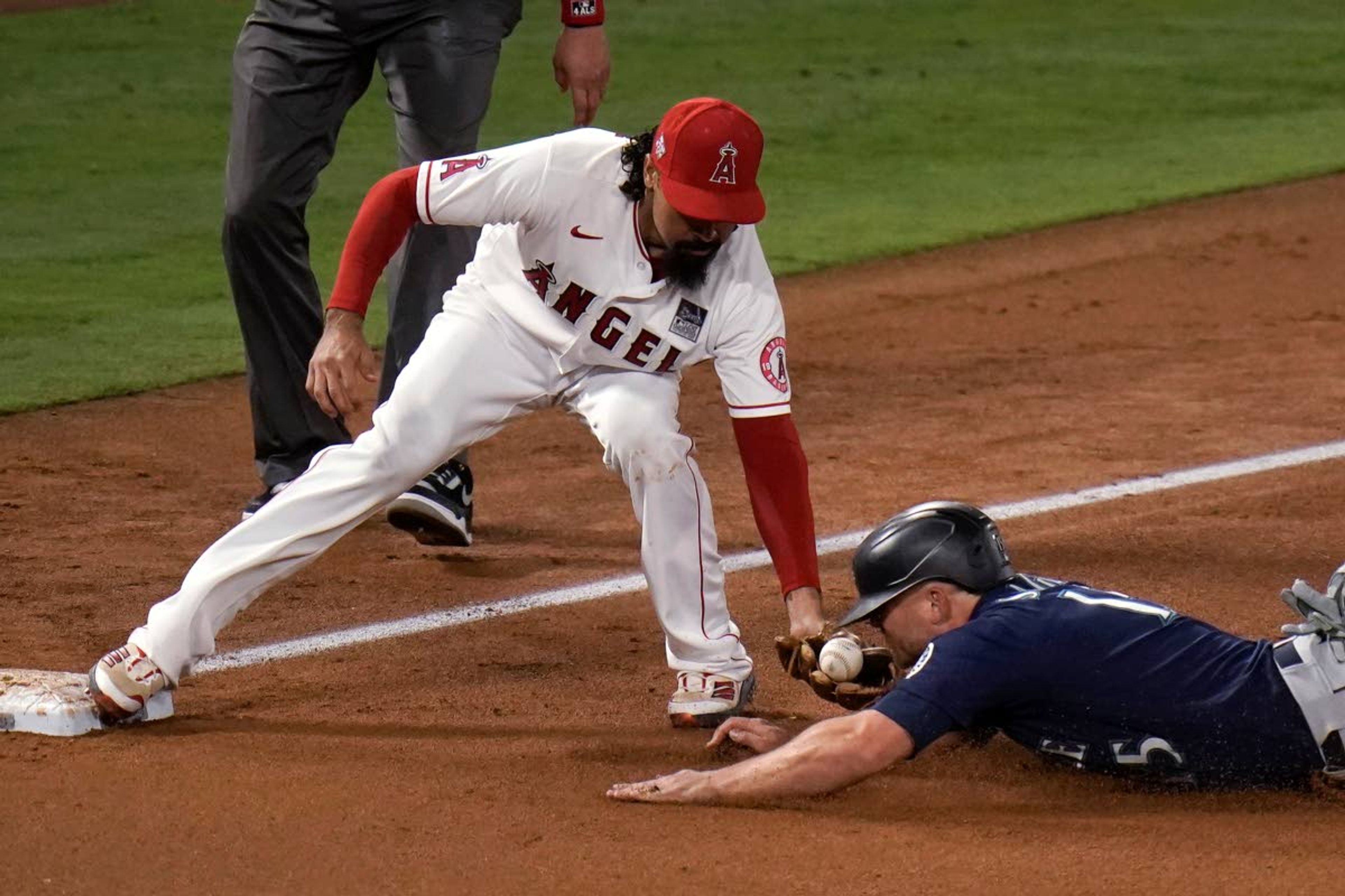 The ball comes out of the glove of Los Angeles Angels third baseman Anthony Rendon as Seattle Mariners' Kyle Seager slides into third base for a steal during the fifth inning of a baseball game in Anaheim, Calif., Thursday, June 3, 2021. (AP Photo/Jae C. Hong)