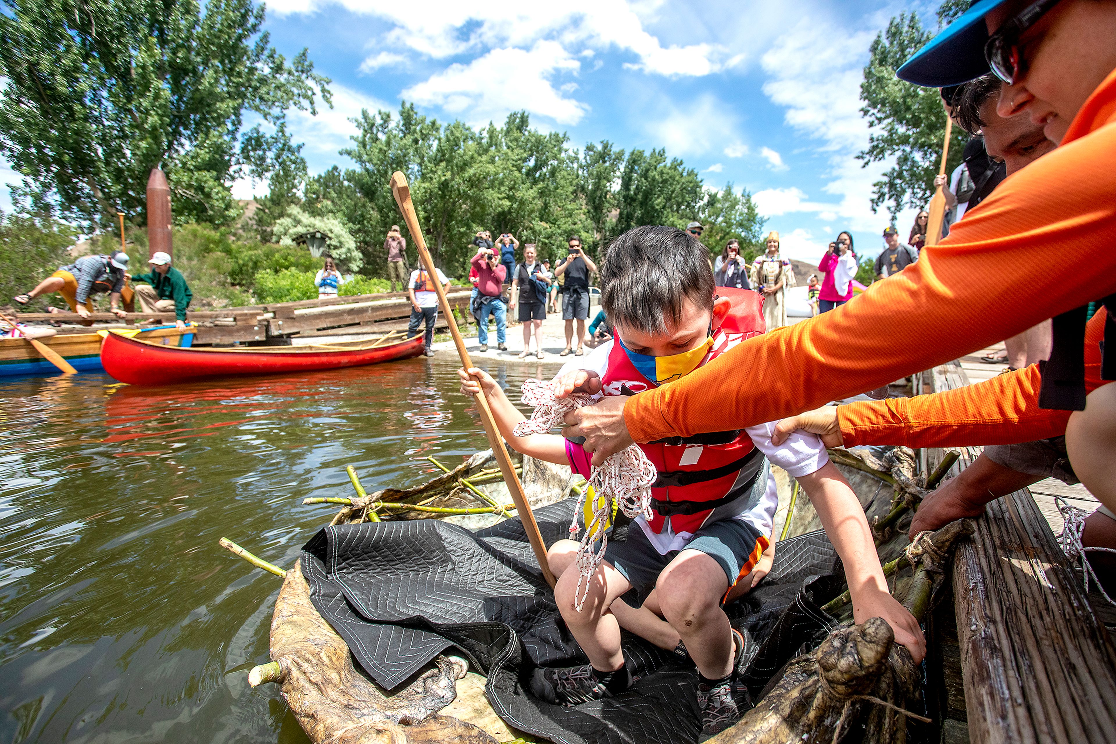 Kids from Palouse Prairie Charter School get in the bull boat constructed out of willow branches and moose hide at Chief Timothy Park on Monday. Ciarra Greene compared the construction of the bull boats, which were made from the buffalo hides men would hunt and willow branches gathered, to the balance between the water and land, and the balance between giving and receiving. These youths are learning those values of balance, Greene said.