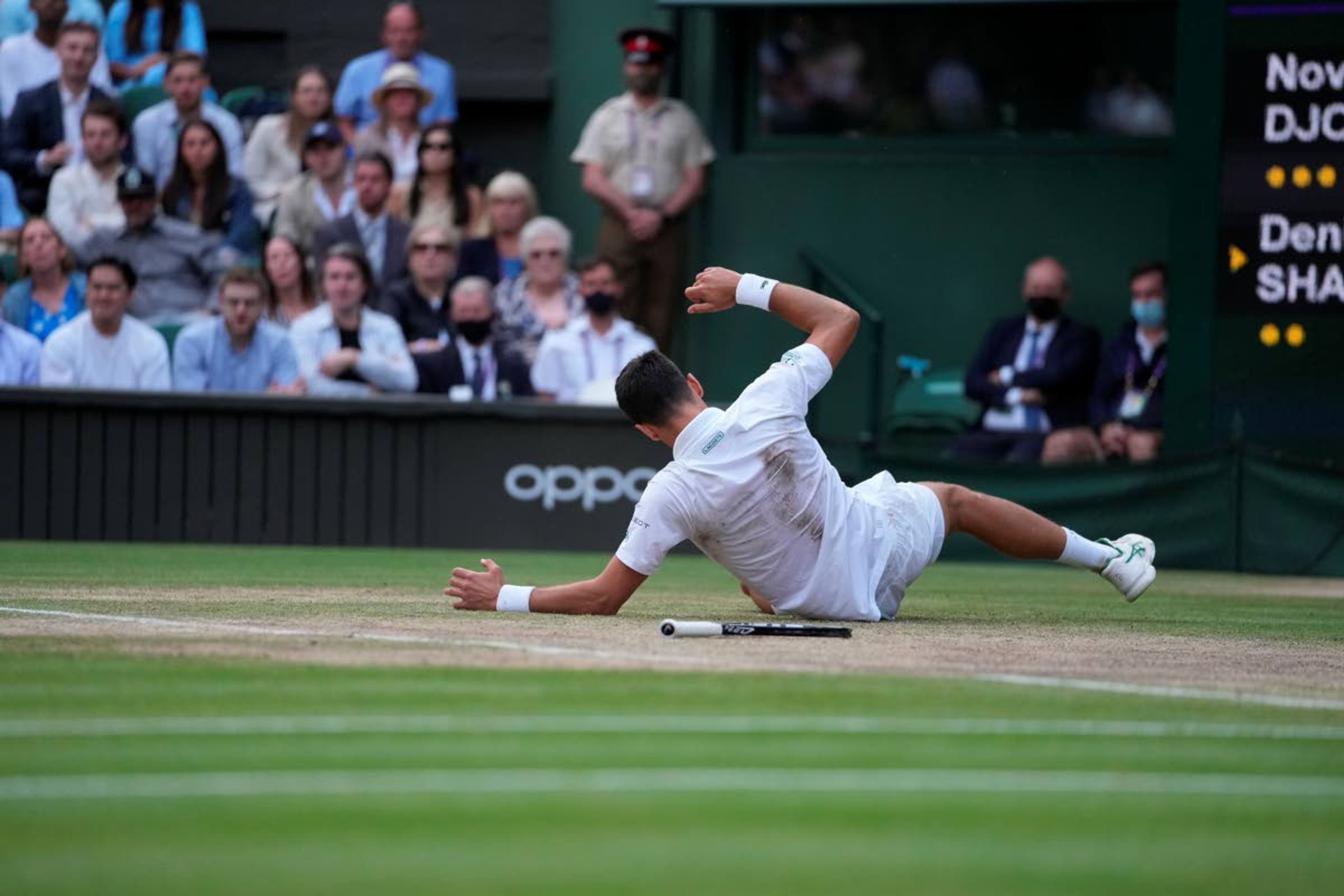 Serbia's Novak Djokovic falls while playing against Canada's Denis Shapovalov during the men's singles semifinals match on day eleven of the Wimbledon Tennis Championships in London, Friday, July 9, 2021. (AP Photo/Alberto Pezzali)