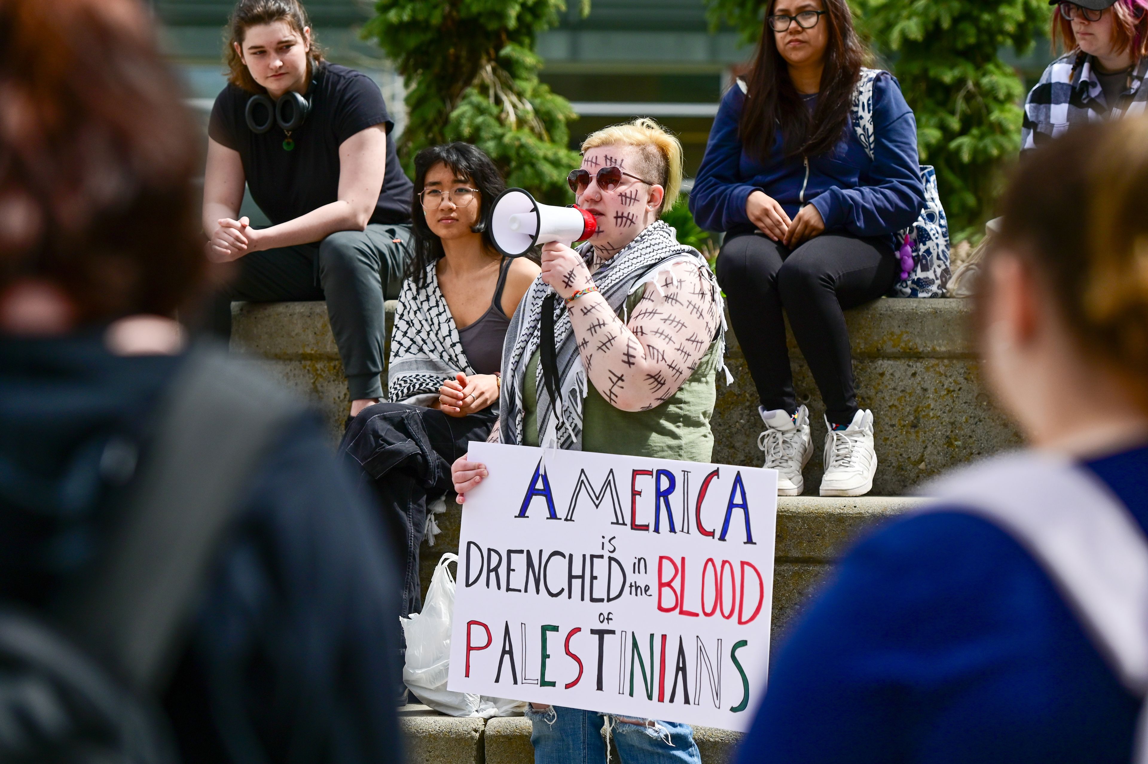 Tallies cover the arms and face of Zeph, a student at the University of Idaho, who speaks to the crowd gathered for a Palestine Week of Action demonstration in Moscow on Thursday. Each tally represents 20 Palestinian children lost in attacks on Gaza, Zeph said.