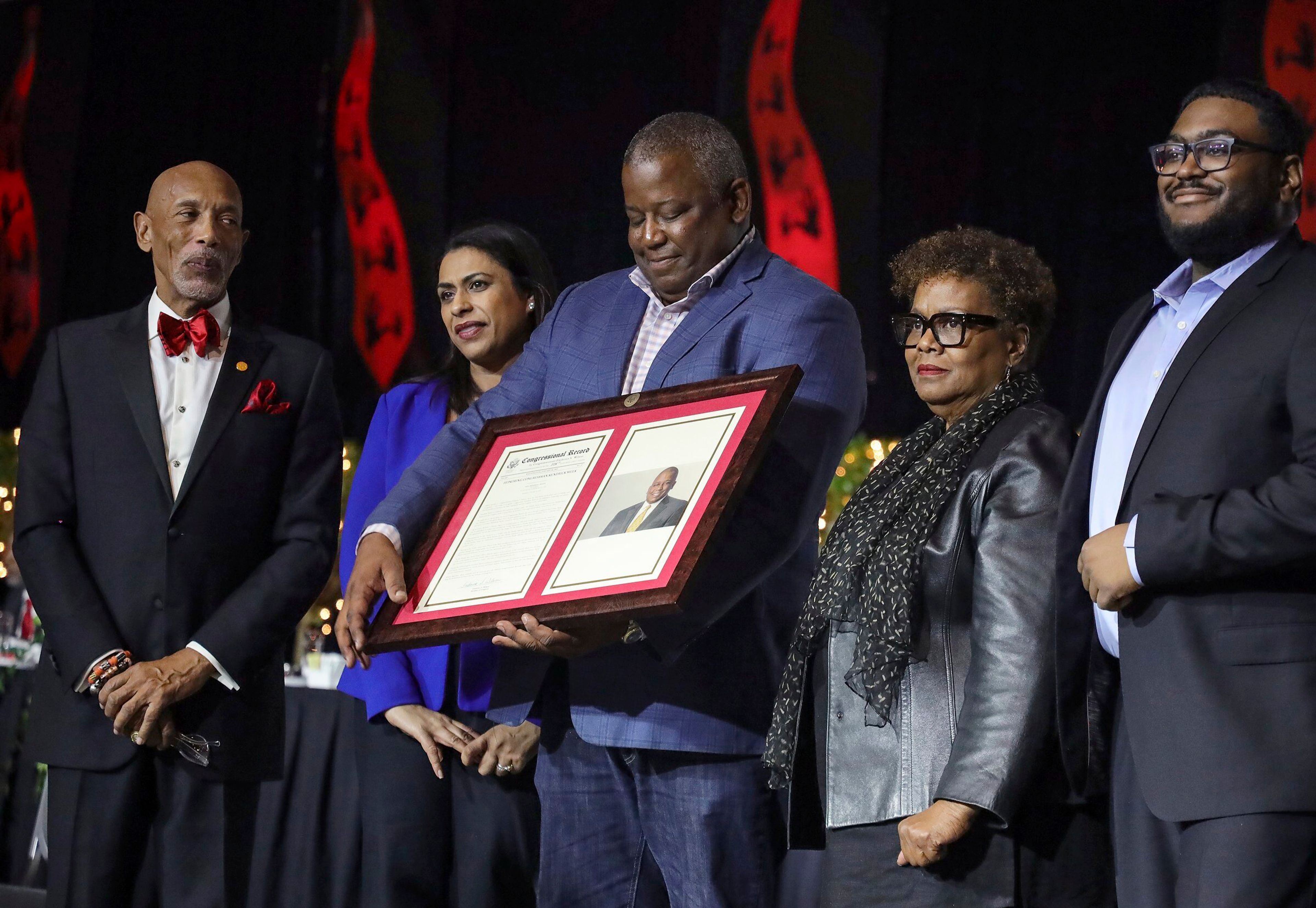 Toastmaster Gordon Eric Knowles, left, looks on as 5000 Role Models of Excellence Foundation 2023 honoree former Congressman Kendrick Meek, center, looks down at his Congressional Record while standing next to his wife Arshi Siddiqui Meek, second left, along with his family during the Annual Dr. Martin Luther King, Jr. Scholarship Breakfast Monday, Jan. 16, 2023, at the Miami Beach Convention Center. Seven Congressional Records were given during the event. (Carl Juste/Miami Herald via AP)