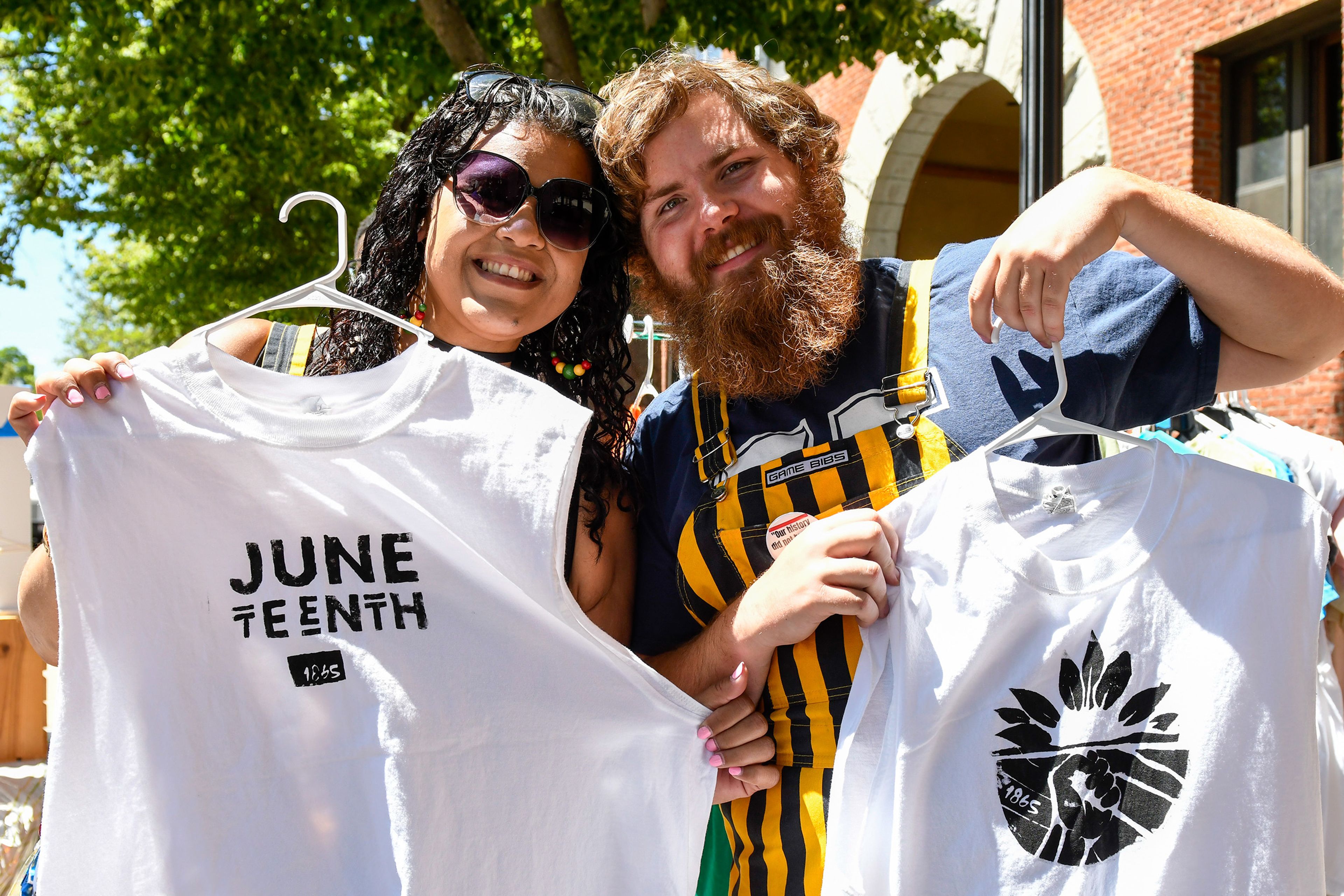 Bex Riehm, left, of the University of Idaho’s Black and African American Cultural Center, and boyfriend C.J. Fitzgerald, a member of the school of Music at UI, hold up shirts made by Riehm, who plans to donate the earnings from the shirts and crafts, at the Juneteenth celebration in Friendship Square on Wednesday in Moscow.