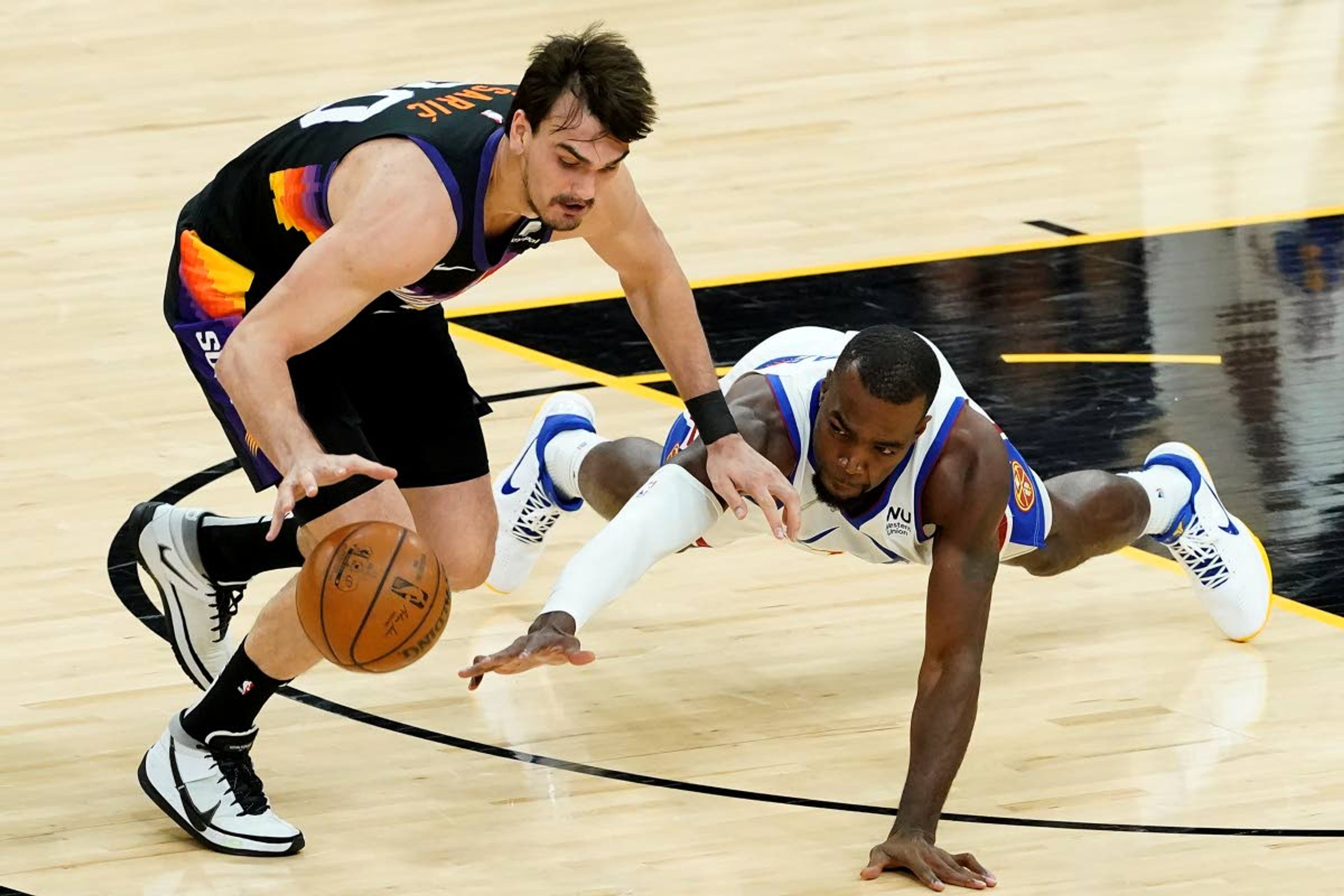 Phoenix Suns forward Dario Saric, left, and Denver Nuggets forward Paul Millsap chase down a loose ball during the first half of Game 2 of an NBA basketball second-round playoff series, Wednesday, June 9, 2021, in Phoenix. (AP Photo/Matt York)