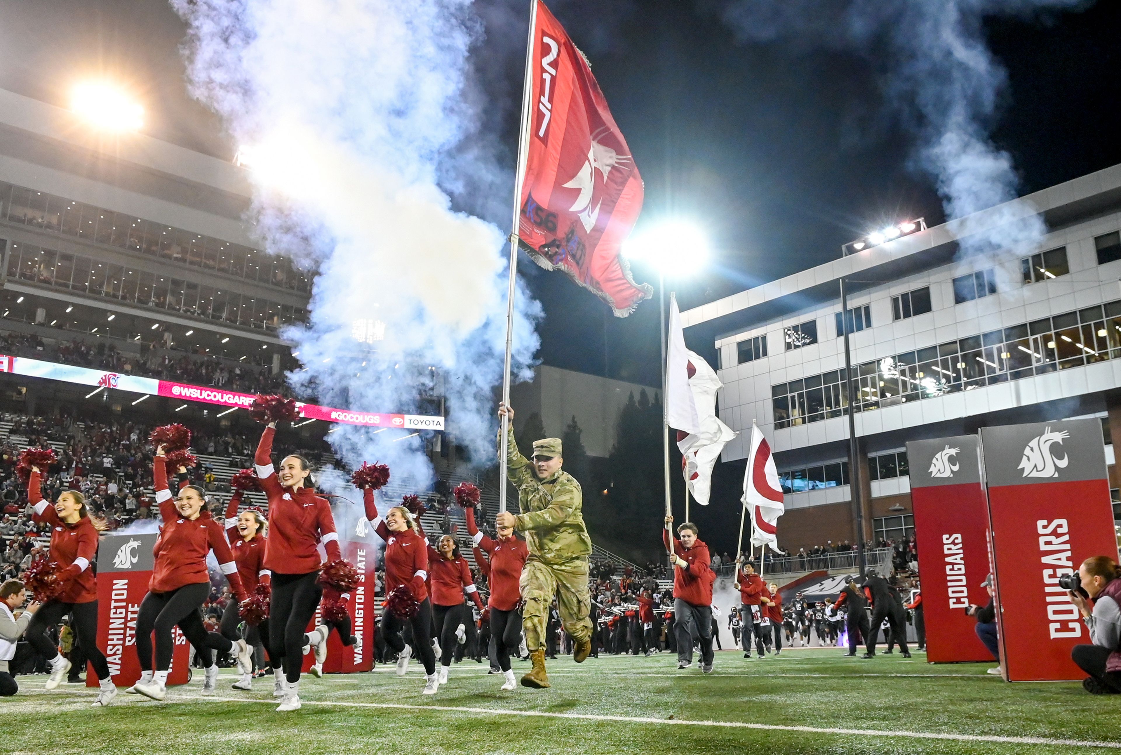 A Washington State Army ROTC student carries a flag across the field Saturday before the start of Washington State’s game against Utah State, the school’s Military Appreciation Game, at Gesa Field in Pullman.