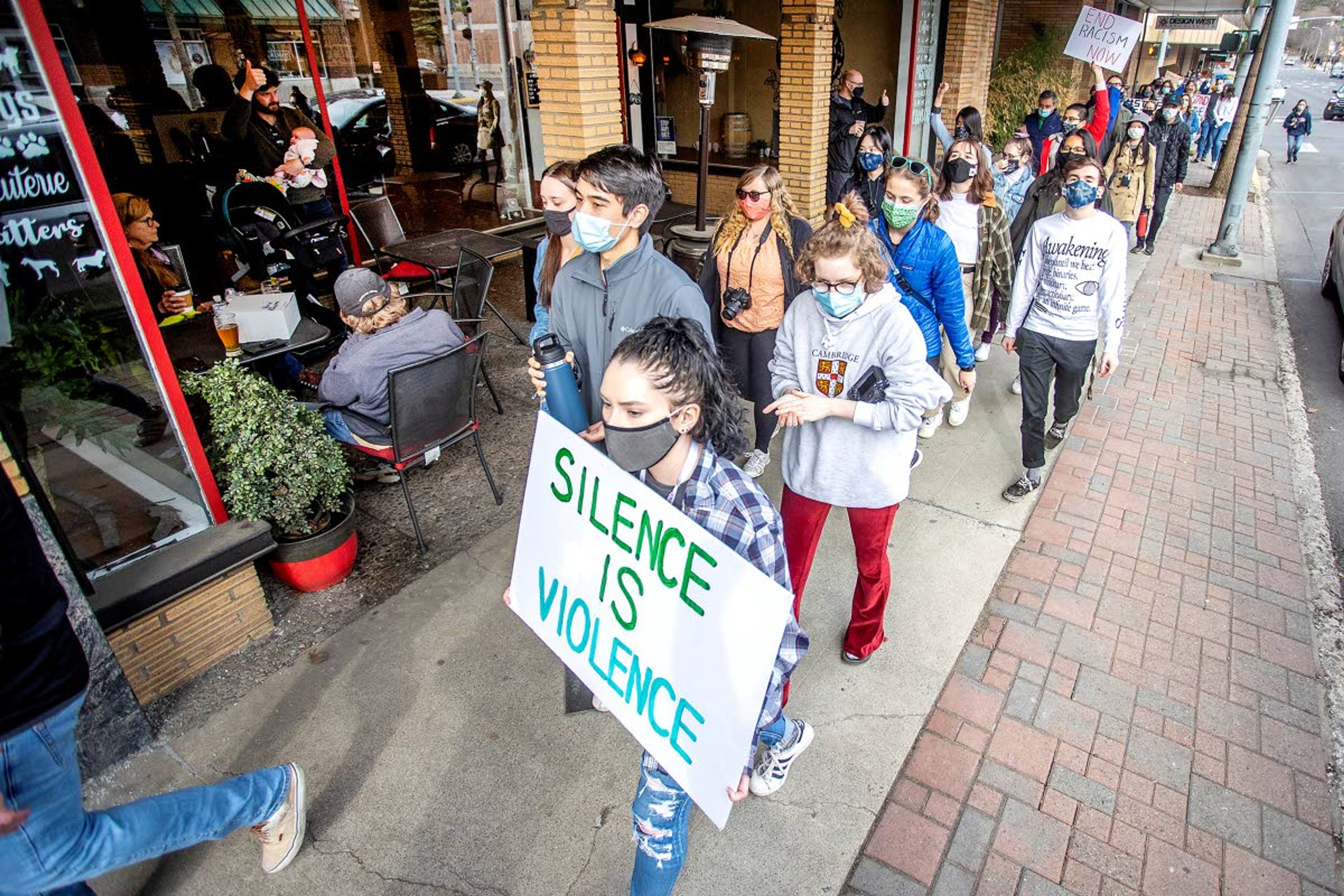 People at a downtown Pullman restaurant give rally participants thumbs up at they pass by.