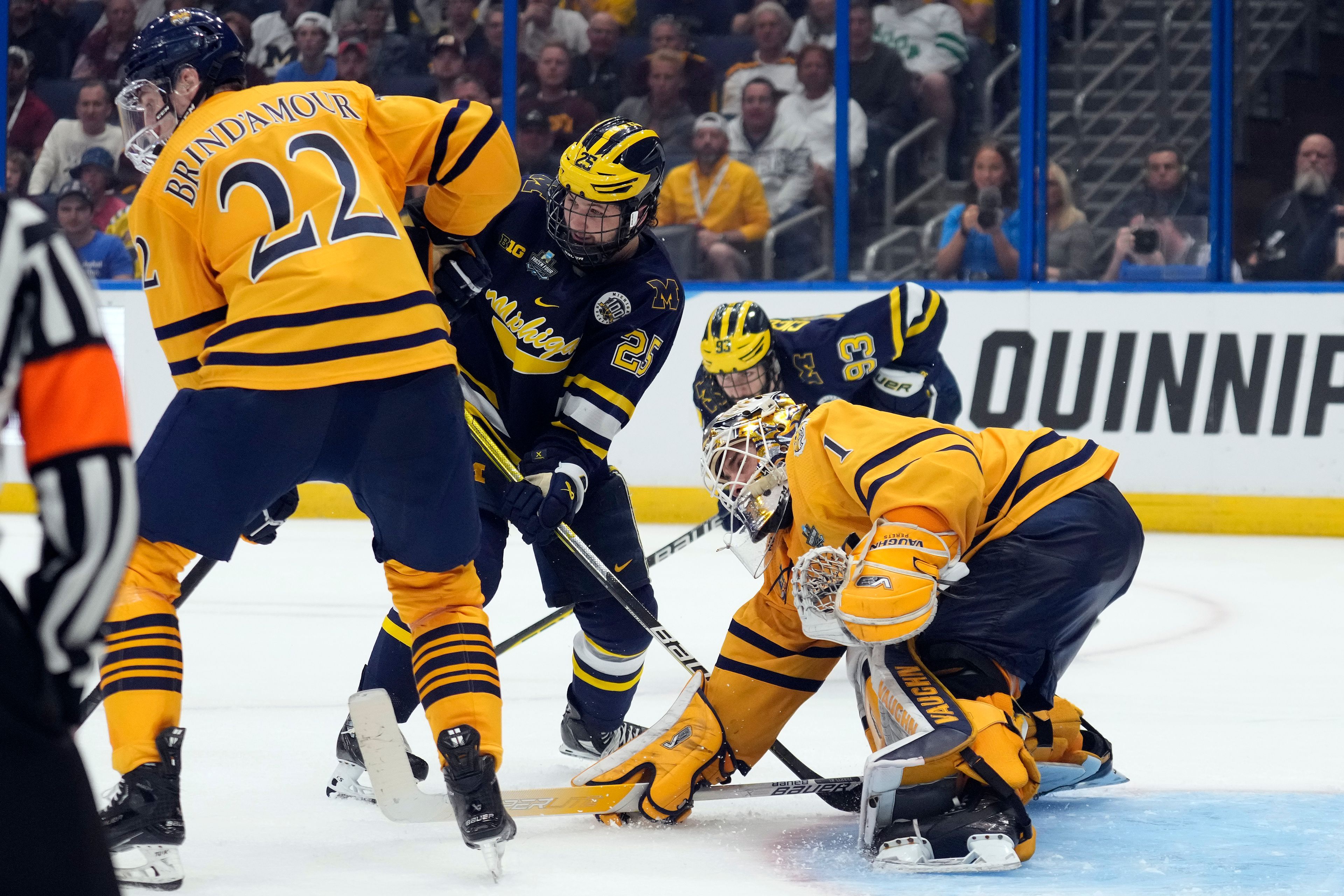 Quinnipiac goaltender Yaniv Perets (1) makes a stick save on a shot by Michigan during the third period of an NCAA semifinal game in the Frozen Four college hockey tournament Thursday, April 6, 2023, in Tampa, Fla. Looking on is forward Skyler Brind'Amour (22), forward Dylan Duke (25), and forward Eric Ciccolini (93). (AP Photo/Chris O'Meara)