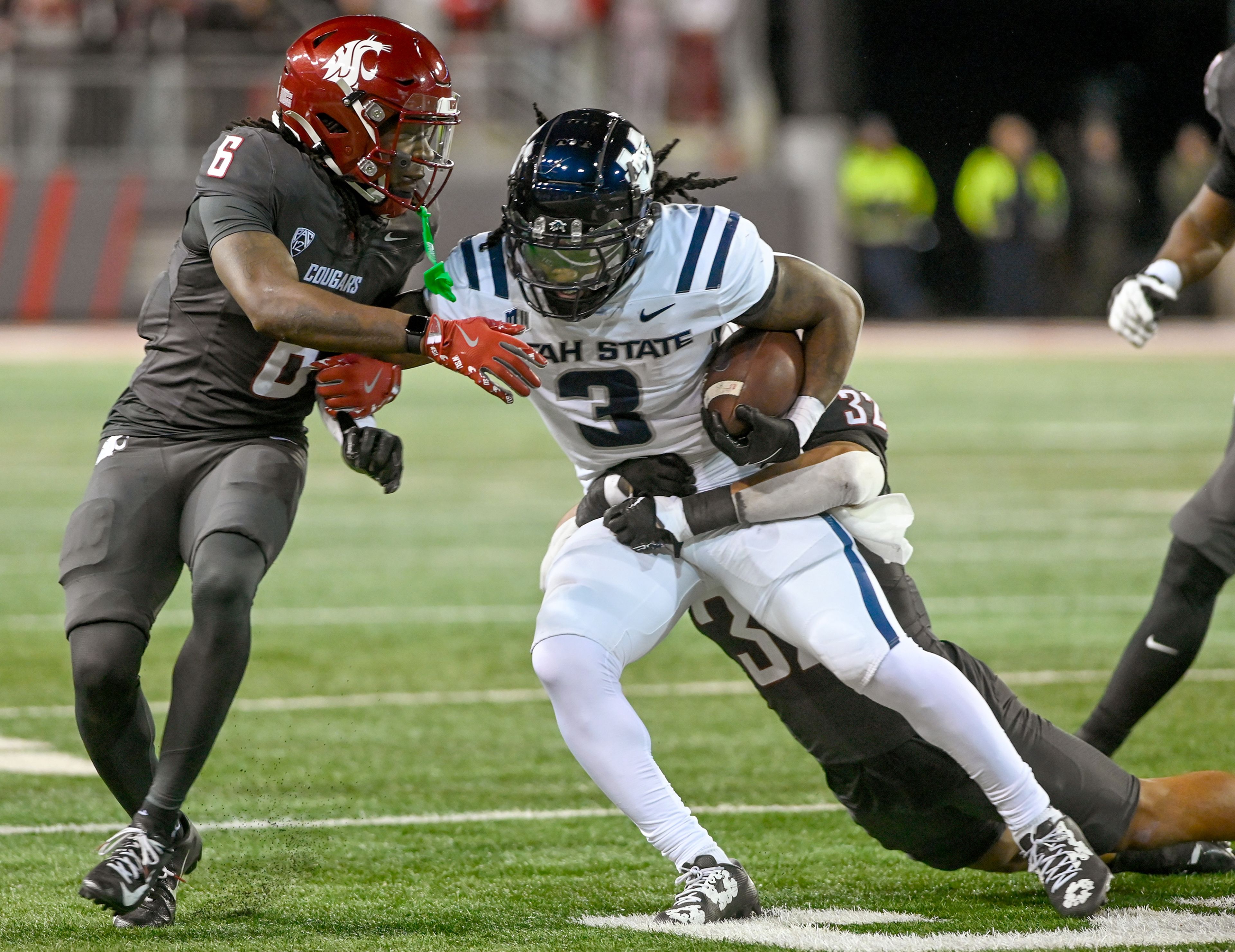 Washington State defensive back Adrian Wilson (6) and Washington State defensive back Tanner Moku (32) tackle Utah State running back Rahsul Faison (3) Saturday at Gesa Field in Pullman.