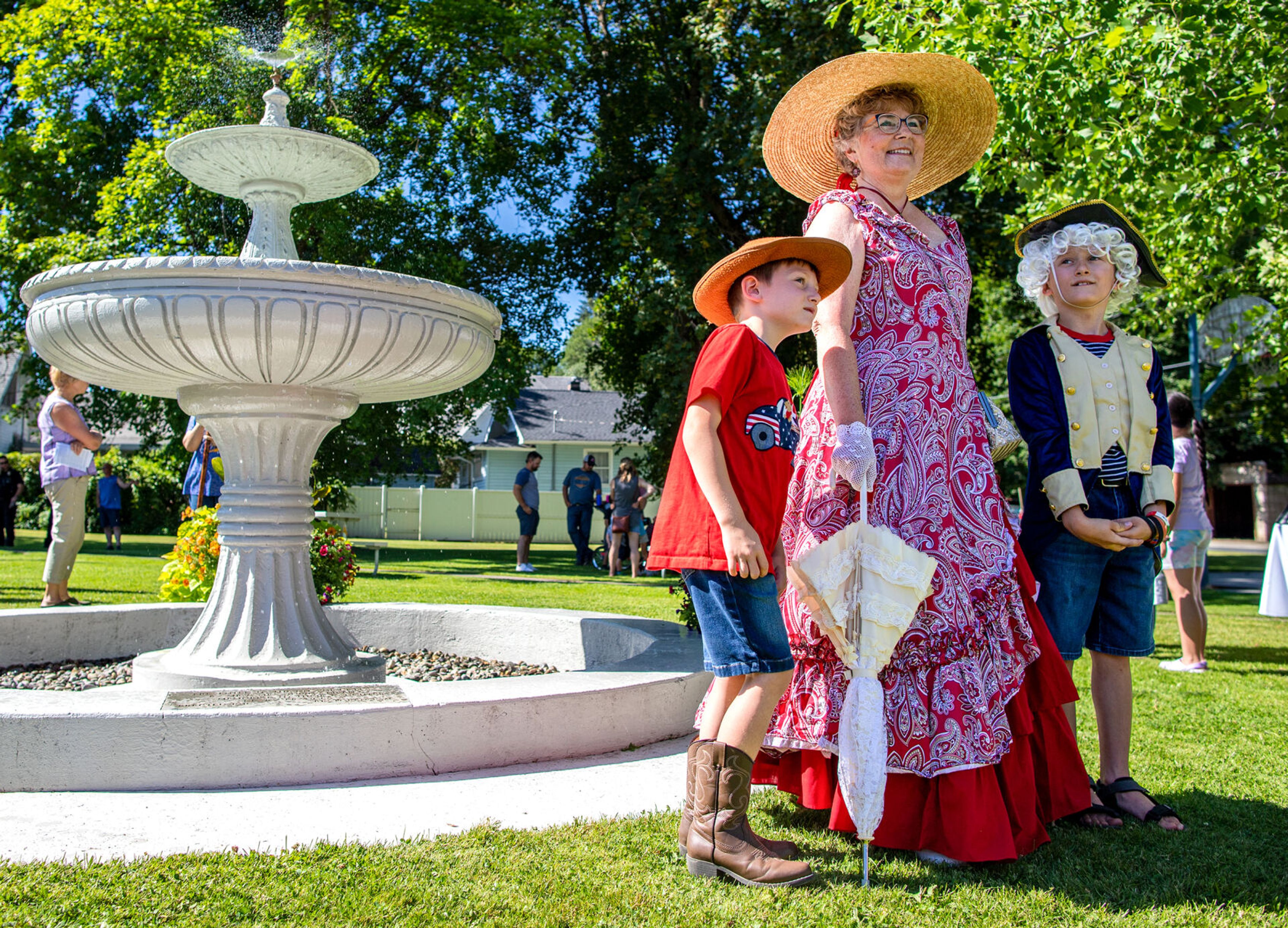 Easton Harrison, 8, right, and his younger brother Beckett, 6, both from Colfax, pose with Perkins House Outreach Coordinator Jill Gfeller on Saturday in front of Lippett Fountain at Colfax’s Eells Park during the city’s 150th birthday celebration.