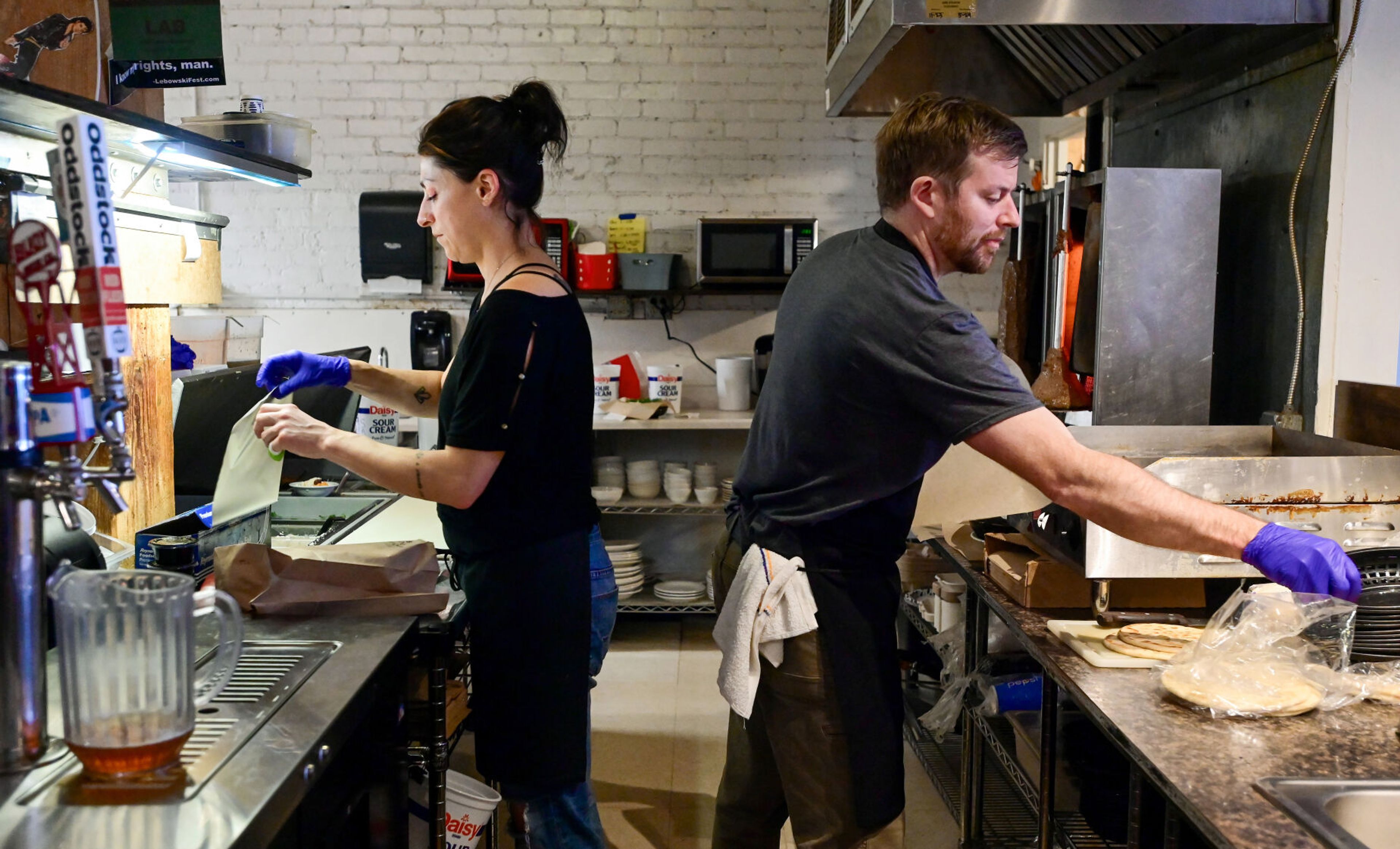 New co-owners of Mikey's Gyros Mina Ashkannejhad, left, and Jeremy Martin work on orders behind the counter of the Greek restaurant in downtown Moscow on Wednesday.