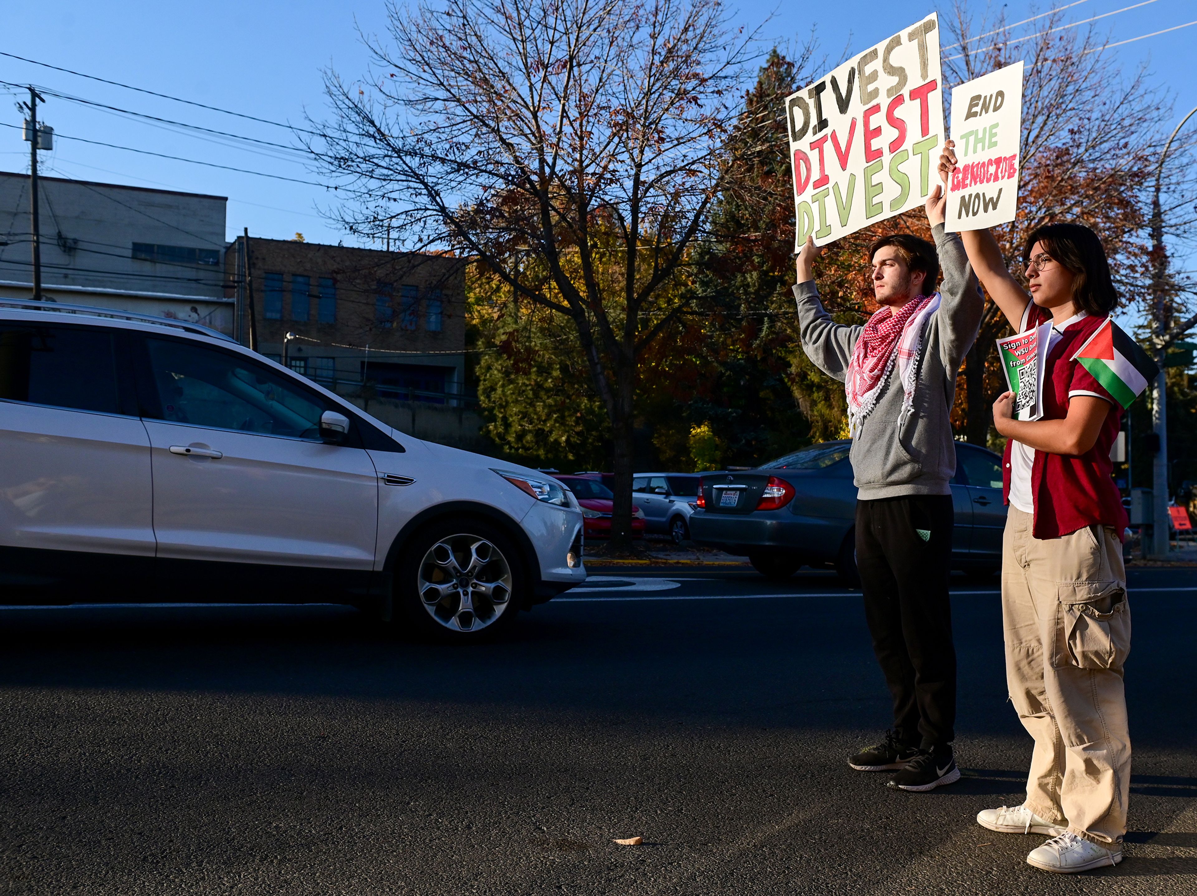 Washington State University students Connor Luce, left, and Bobby Selden raise their signs to face traffic moving along Grand Avenue after marching from campus to downtown with a Pullman for Palestine rallying group Monday in Pullman.