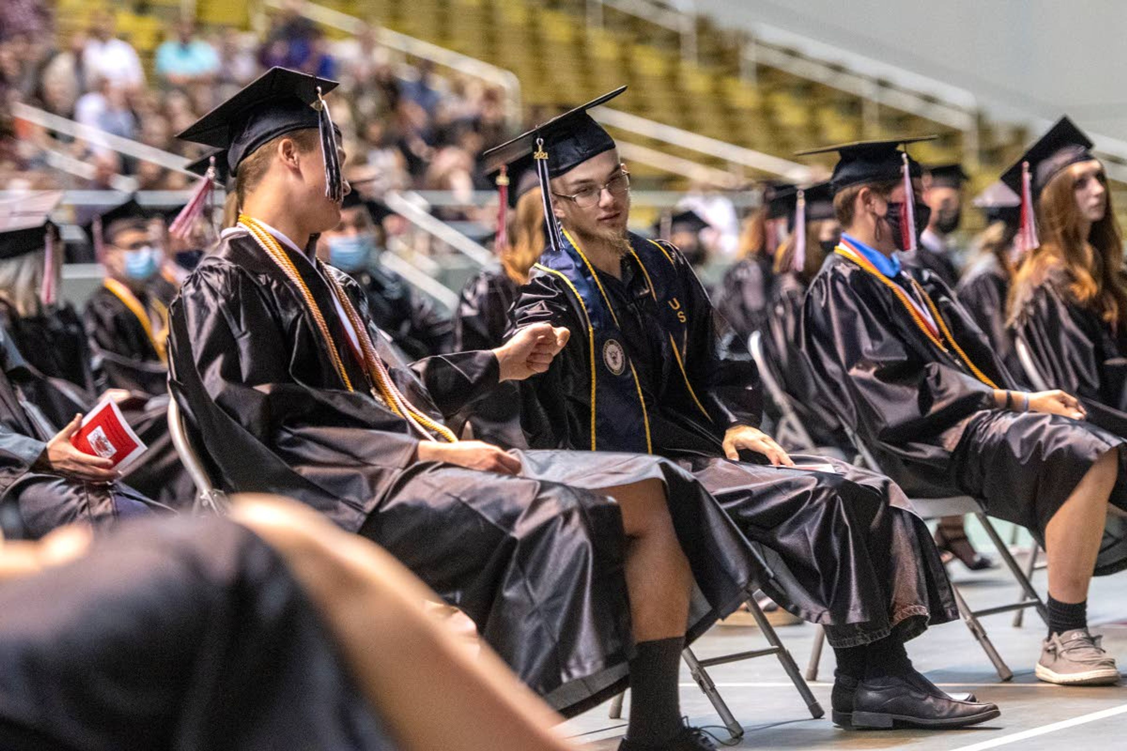 Graduating seniors fist-bump one another during Moscow High School’s Class of 2021 graduation commencement at the University of Idaho’s Kibbie Dome on Friday night.