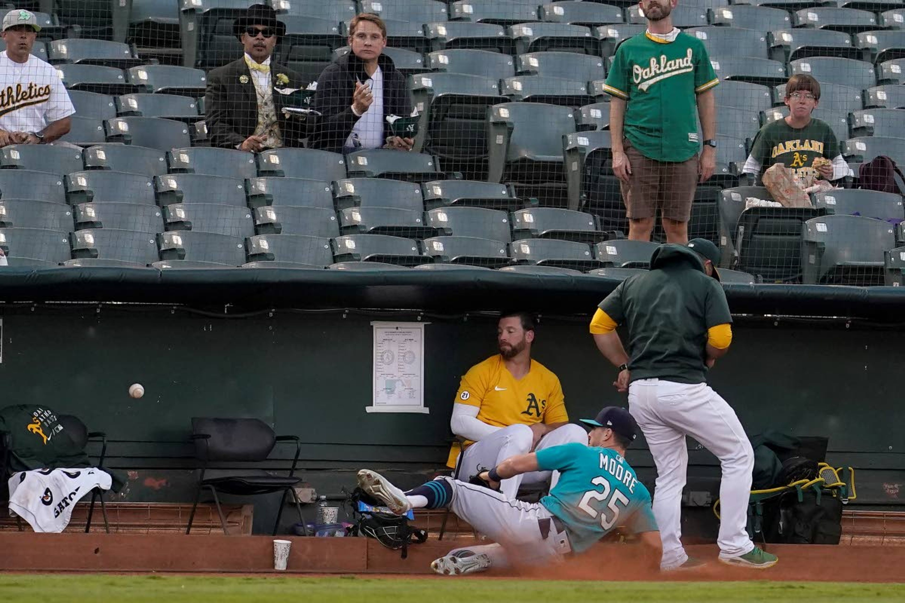 Seattle Mariners left fielder Dylan Moore (25) cannot catch a foul ball hit by Oakland Athletics' Matt Olson as he slides into the Athletics bullpen during the first inning of a baseball game in Oakland, Calif., Monday, Sept. 20, 2021. (AP Photo/Jeff Chiu)