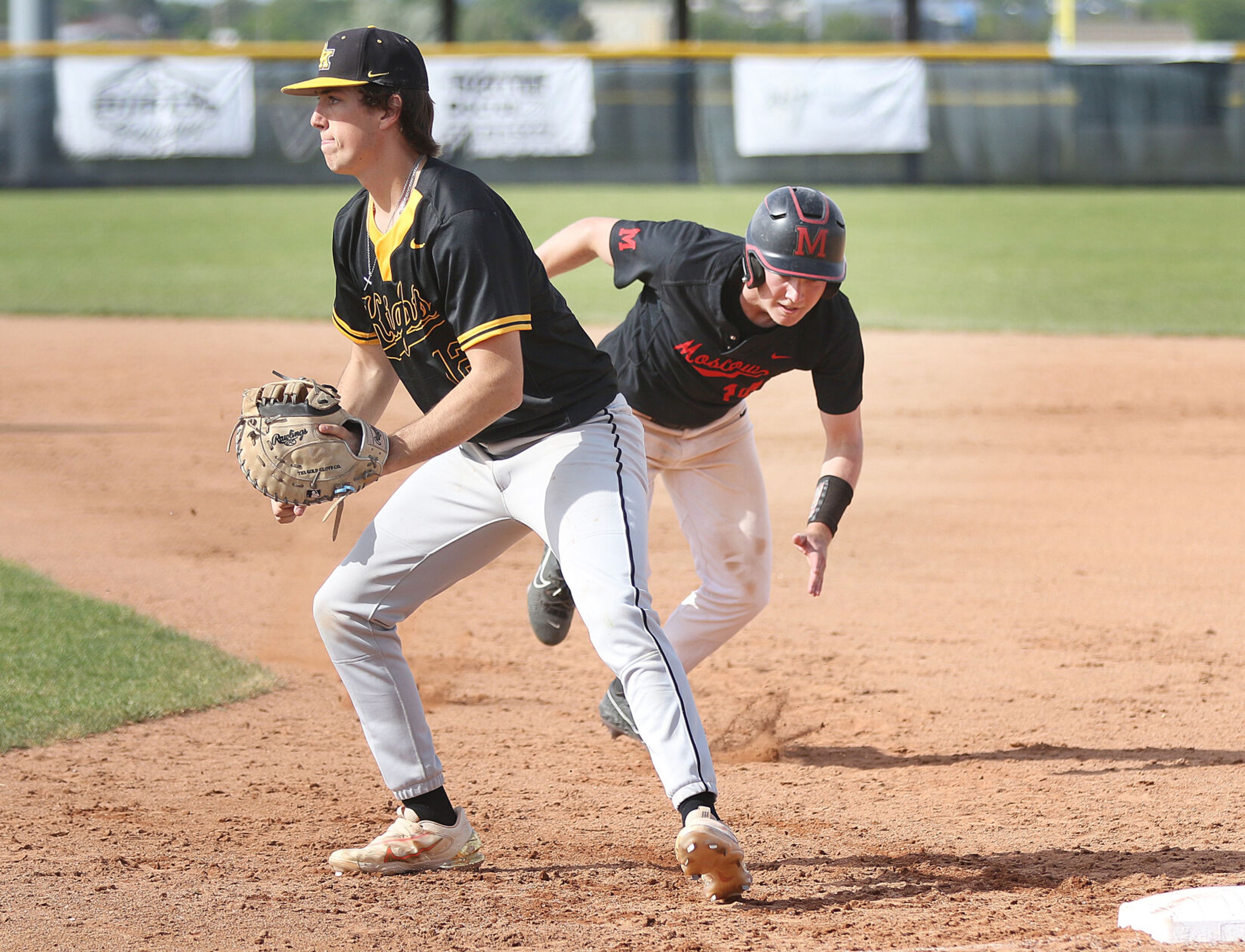 Moscow's Andrew Hurley (right) dives back to first base to avoid a pick-off during the Idaho Class 4A state championship game against Bishop Kelly on Saturday at Vallivue High School in Caldwell, Idaho.