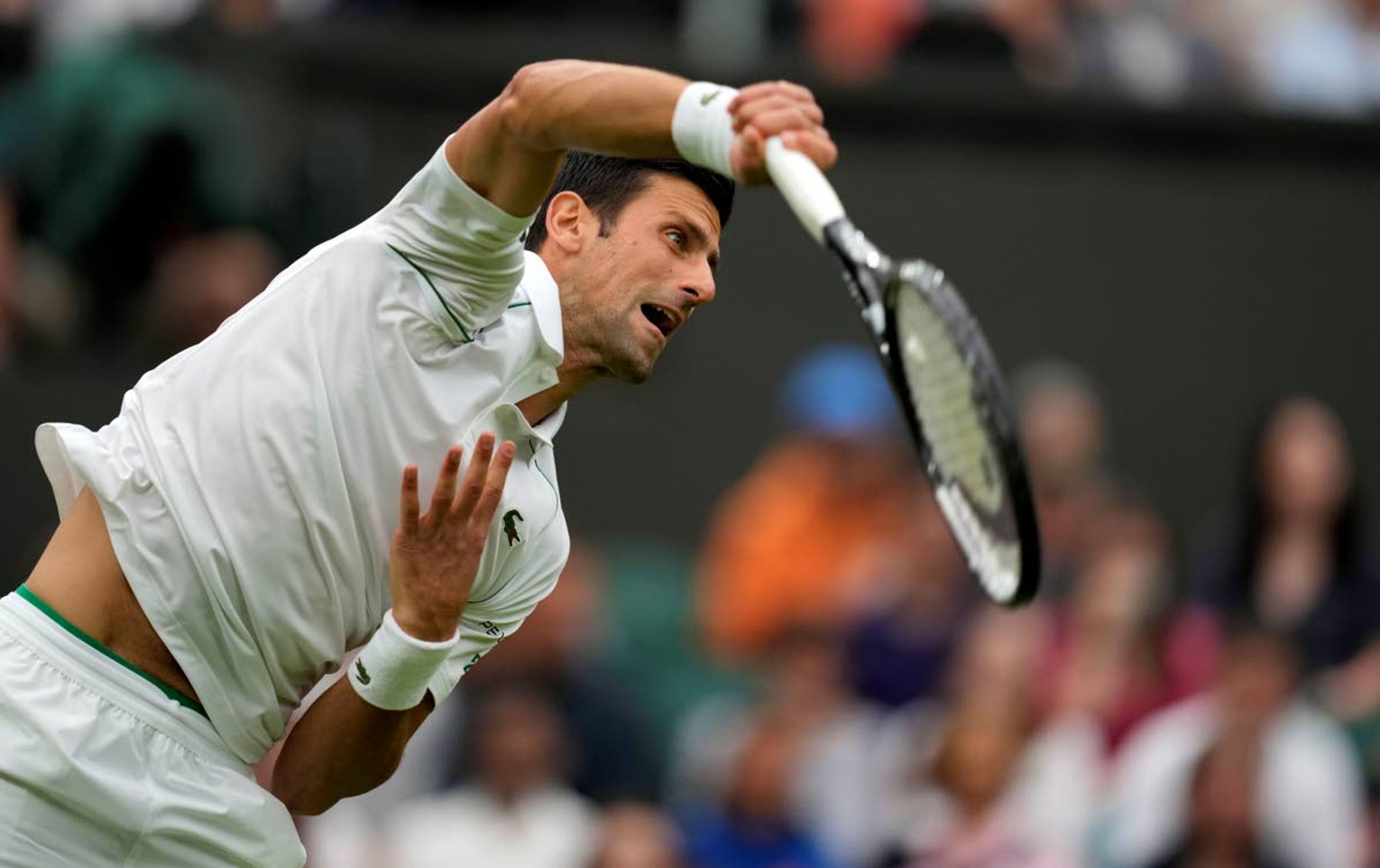 Serbia's Novak Djokovic serves to Britain's Jack Draper during their first round men's singles match on day one of the Wimbledon Tennis Championships in London, Monday June 28, 2021. (AP Photo/Kirsty Wigglesworth)