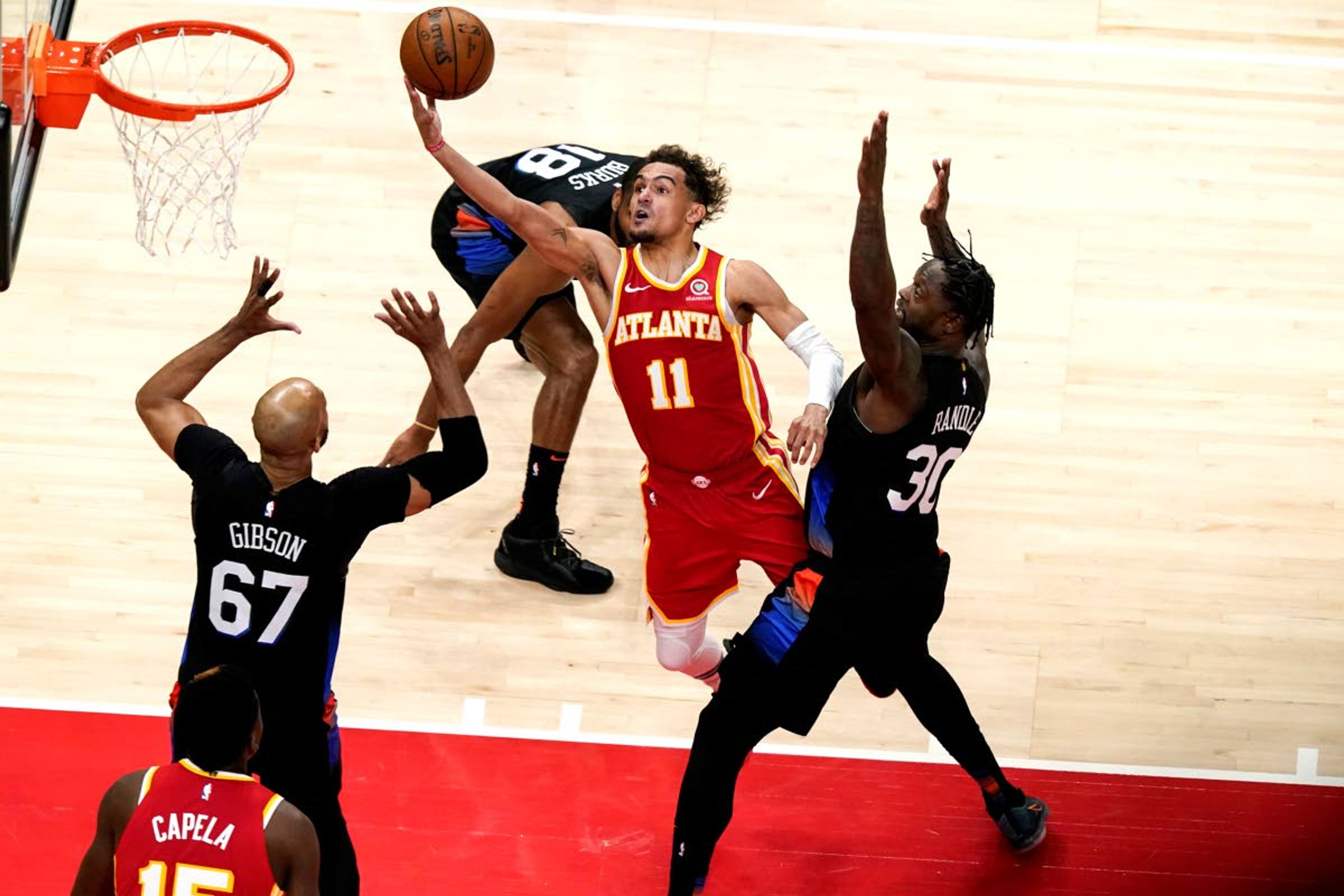 Atlanta Hawks' Trae Young (11) shoots against New York Knicks' Julius Randle (30) and Taj Gibson (67) during the first half in Game 3 of an NBA basketball first-round playoff series Friday, May 28, 2021, in Atlanta. (AP Photo/Brynn Anderson)