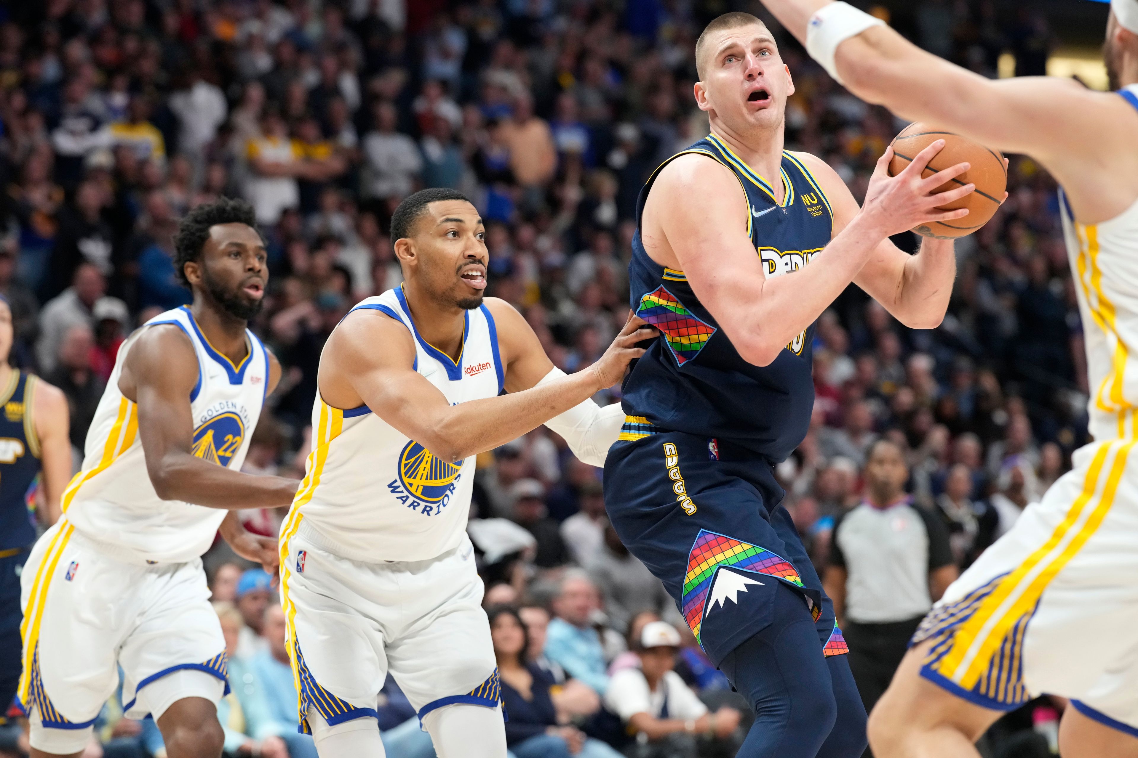 Denver Nuggets center Nikola Jokic, third from left, drives the lane as, from left, Golden State Warriors forward Andrew Wiggins, forward Otto Porter Jr. and guard Klay Thompson defend in the second half of Game 4 of an NBA basketball first-round Western Conference playoff series, Sunday, April 24, 2022, in Denver. (AP Photo/David Zalubowski)