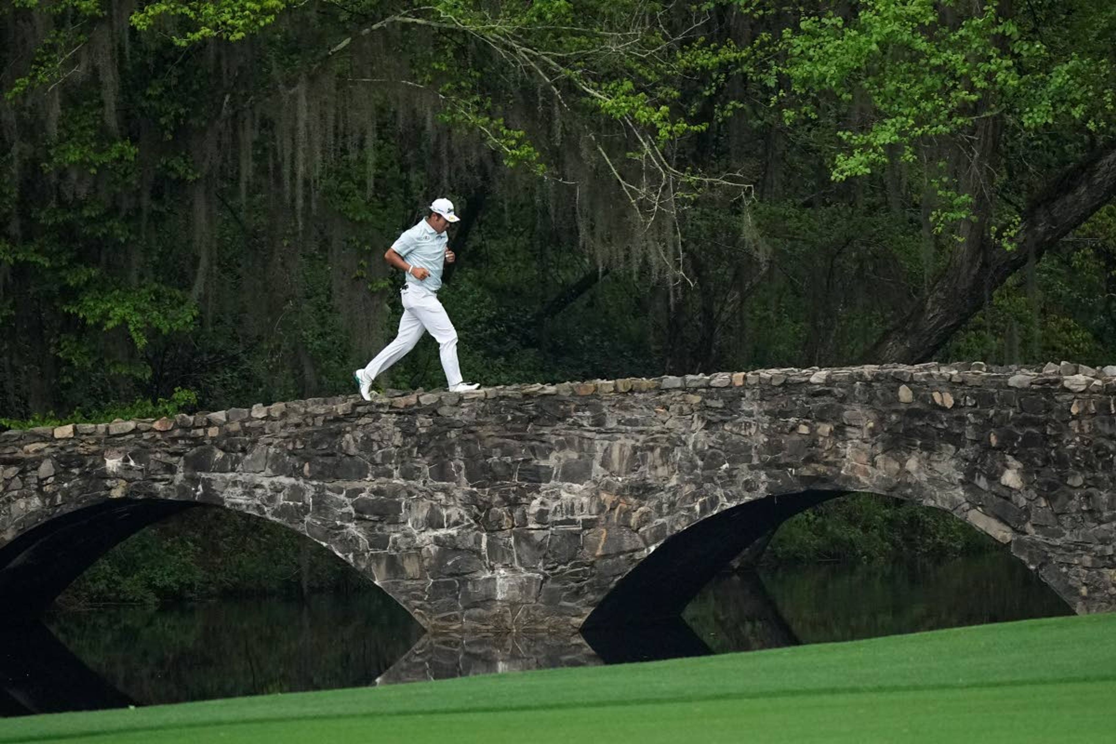 Hideki Matsuyama, of Japan, runs across the Nelson Bridge on the 13th hole during the third round of the Masters golf tournament on Saturday, April 10, 2021, in Augusta, Ga. (AP Photo/David J. Phillip)