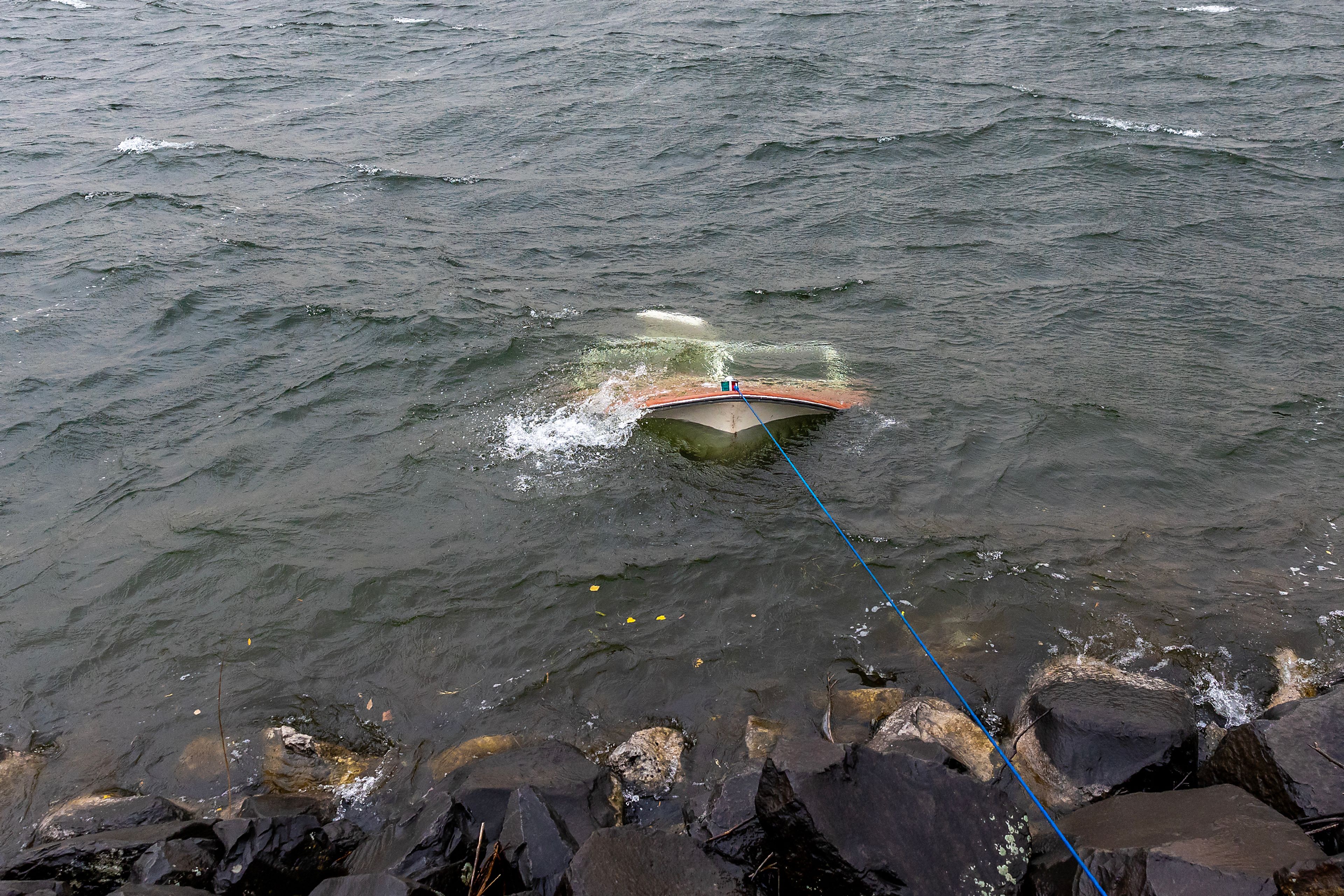 A boat that was blown unto the rocks of the Lewiston Levee sits sunken in the water of the confluence of the Snake and Clearwater rivers Friday. The owner of the boat and a dog made it safely to shore.