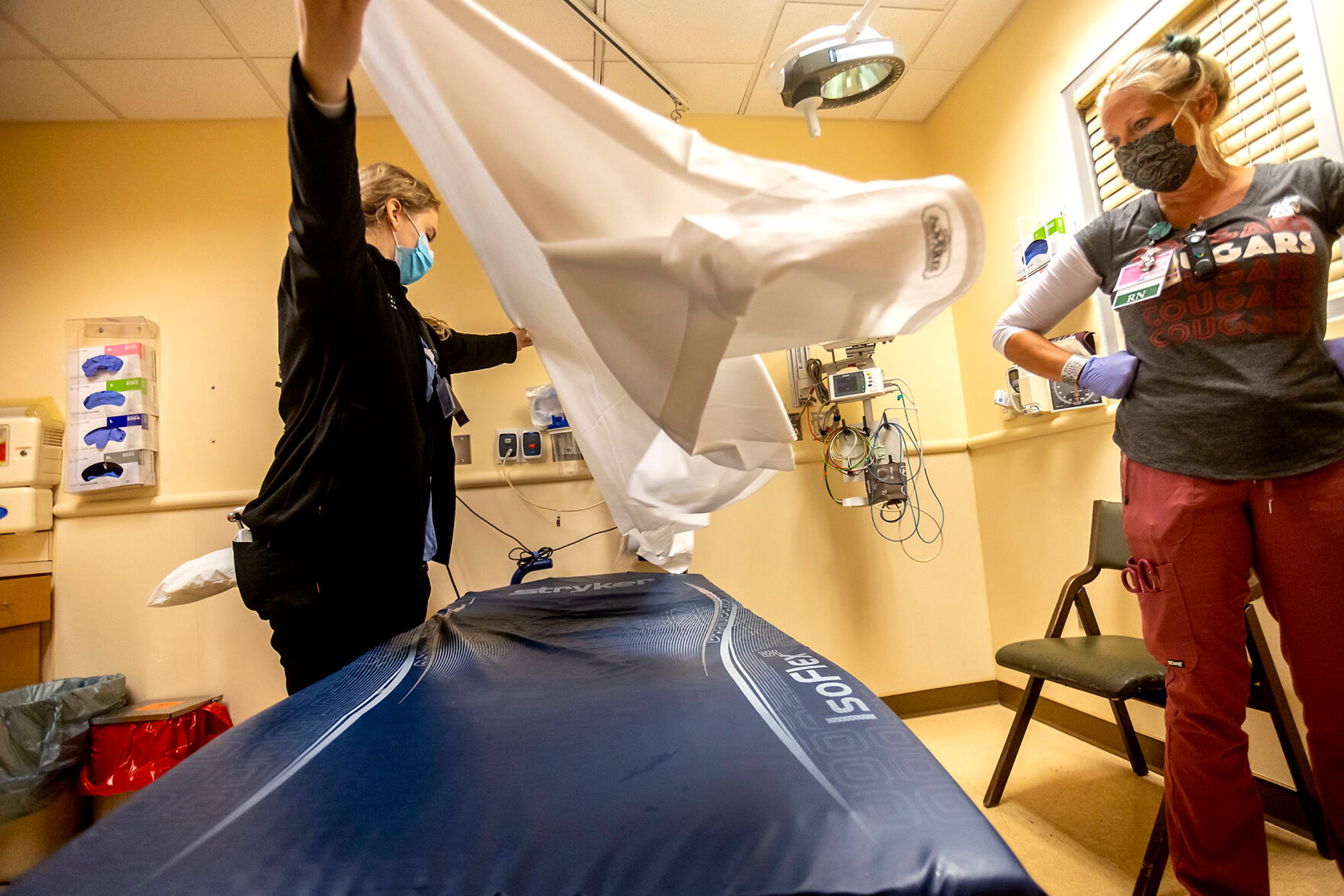 Katie Henneman, left, and Carey Howe quickly wipe down and replace bedding in a room following a patients departure from it at the Pullman Regional Hospital emergency room Sept. 24.