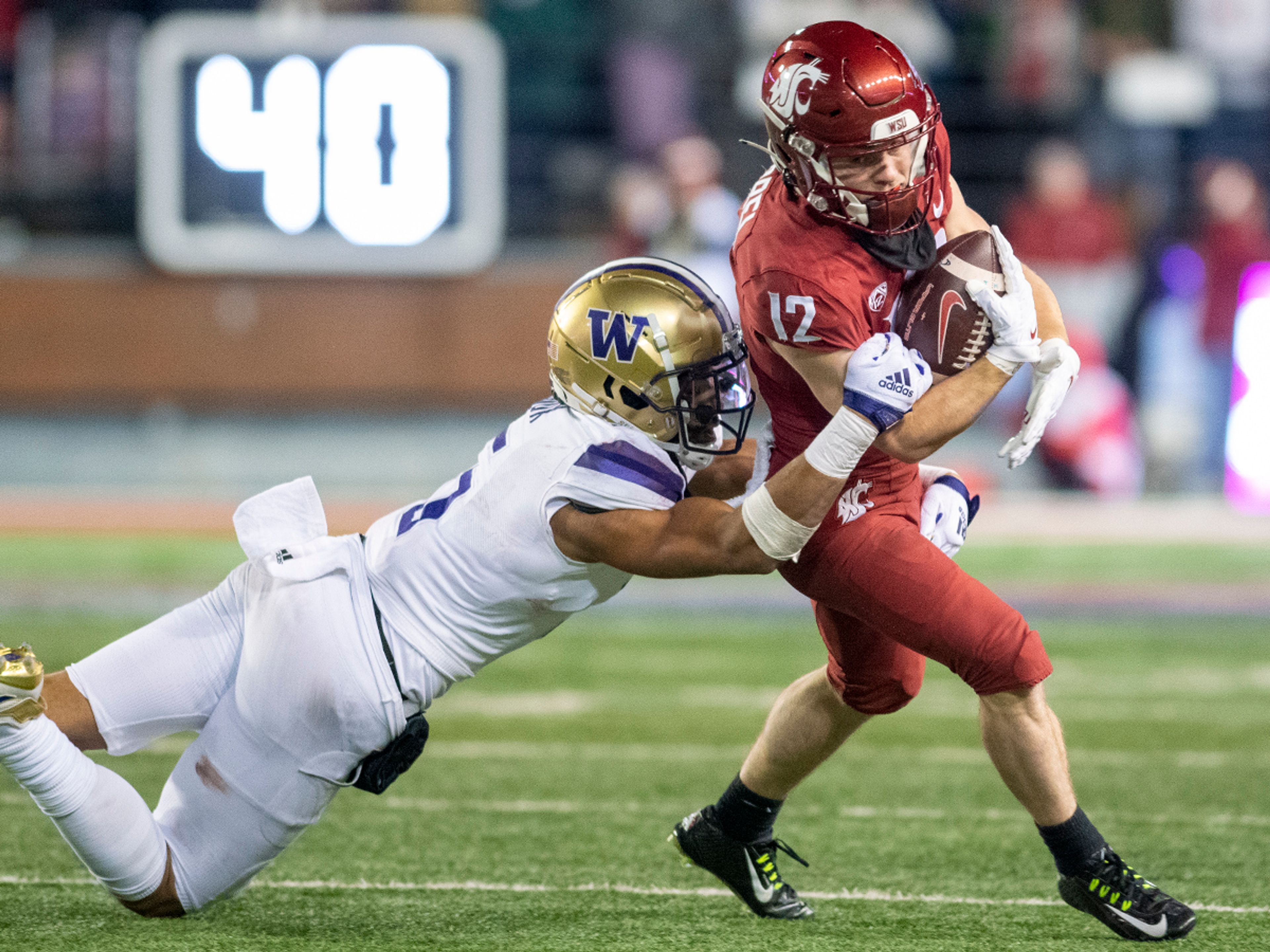 Washington State Cougars wide receiver Robert Ferrel (12) is tackled by Washington Huskies safety Alex Cook (5) during the fourth quarter of the Apple Cup at Gesa Field in Pullman on Saturday.