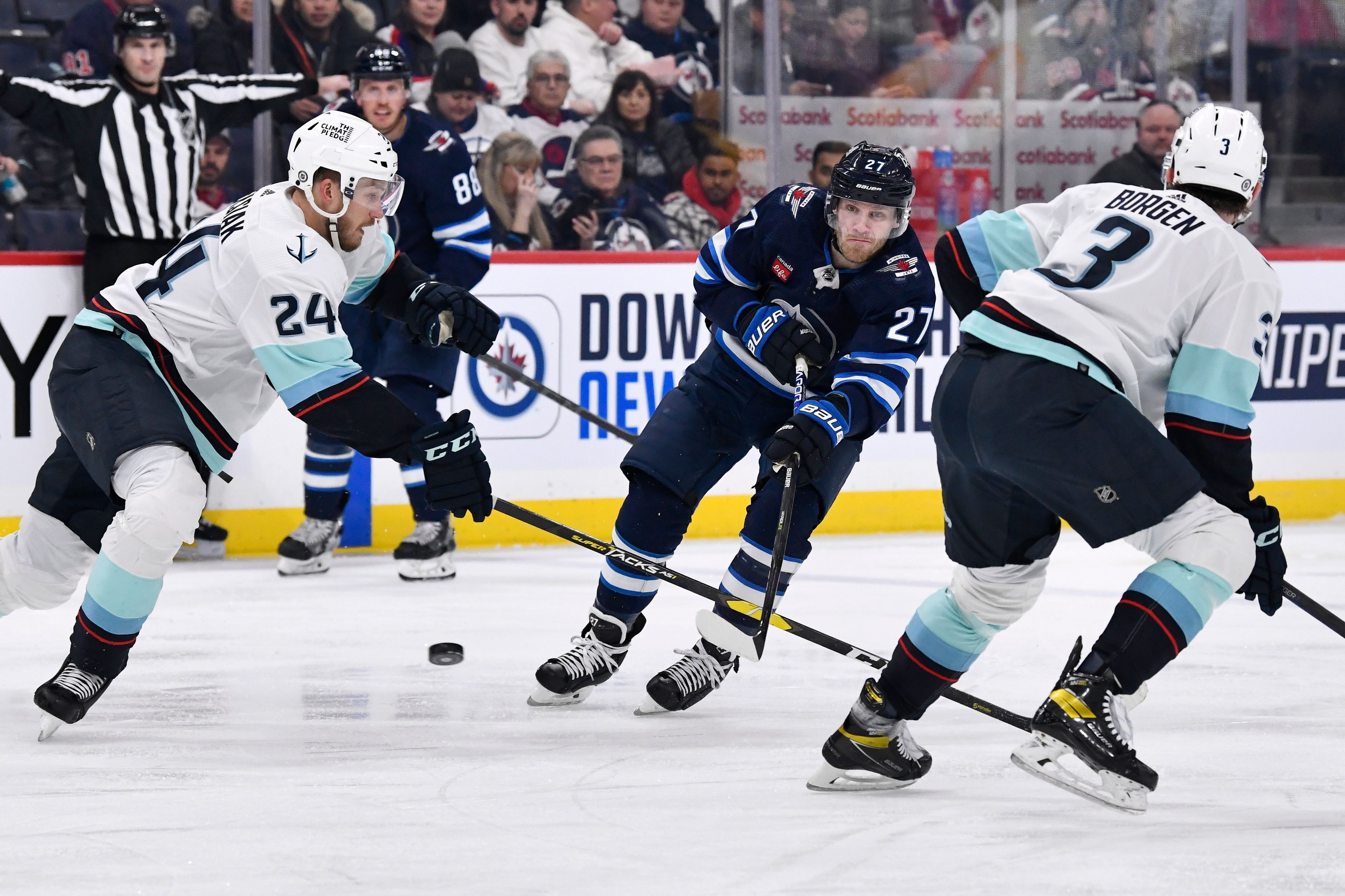 Winnipeg Jets' Nikolaj Ehlers (27) takes a shot between Seattle Kraken's Jamie Oleksiak (24) and Will Borgen (3) during the second period of an NHL game in Winnipeg, Manitoba on Tuesday Feb. 14, 2023. (Fred Greenslade/The Canadian Press via AP)