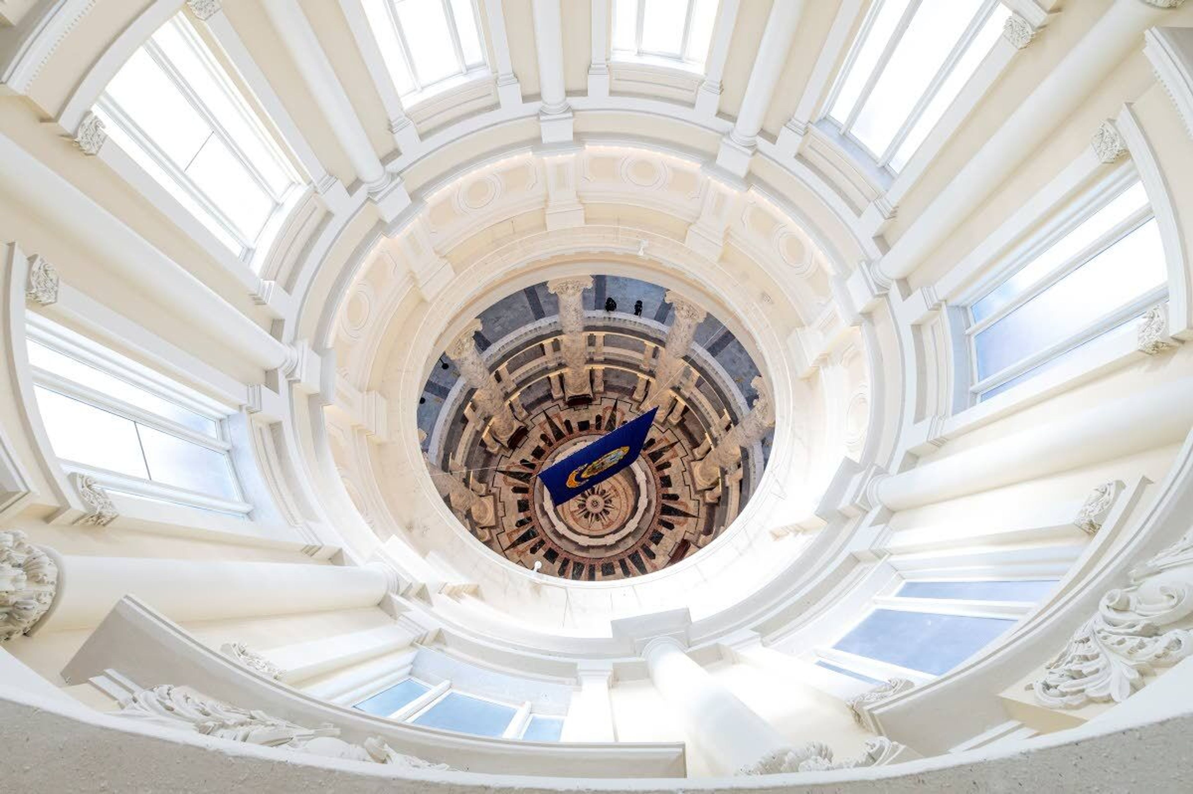 A pair of Idaho State Police Troopers stand on the fourth floor of the Idaho Capitol Building rotunda as light shines in through the large window near the top of the dome on March 27.