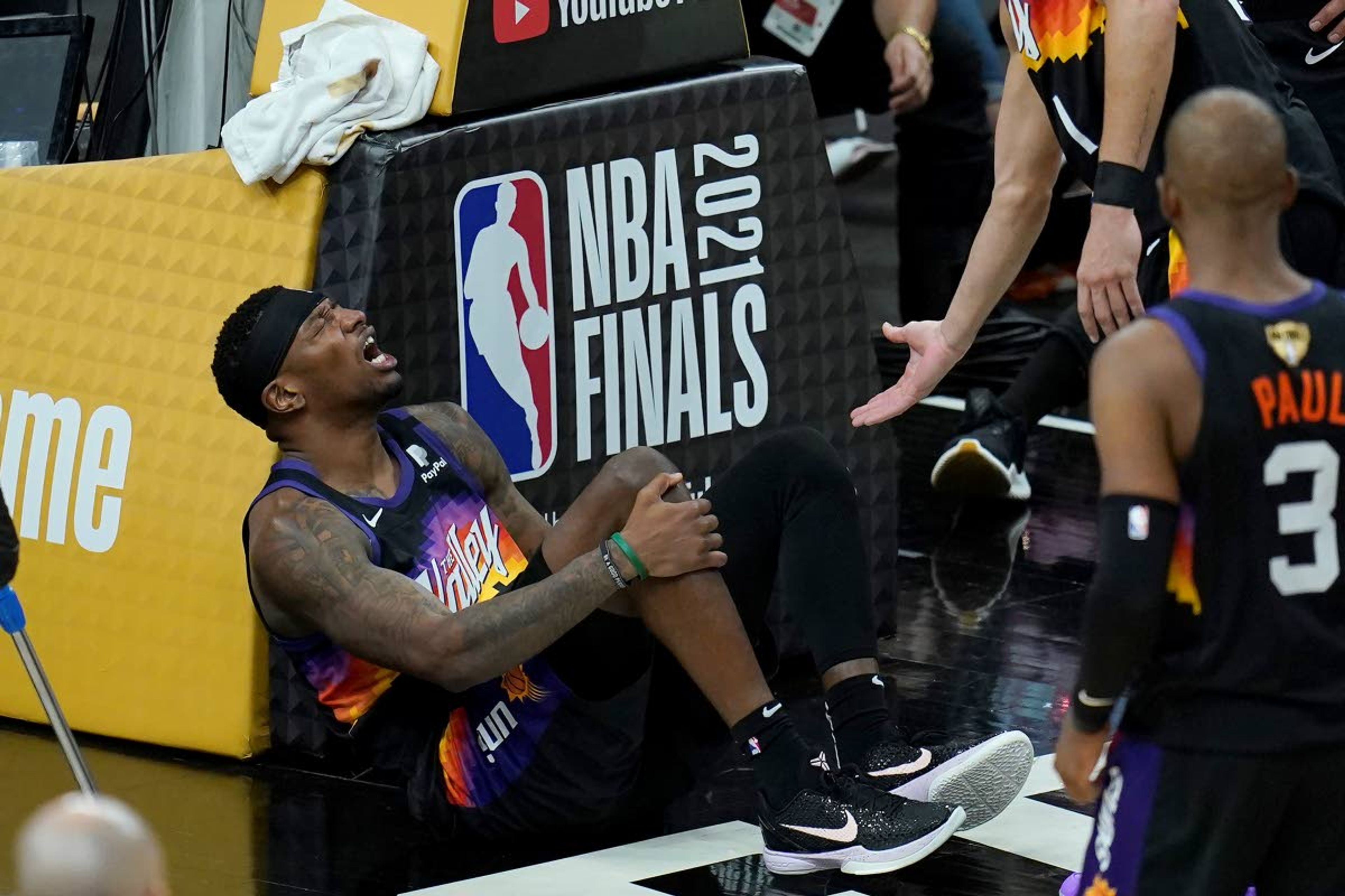 Phoenix Suns forward Torrey Craig grabs his leg during the second half of Game 2 of basketball's NBA Finals against the Milwaukee Bucks, Thursday, July 8, 2021, in Phoenix. (AP Photo/Ross D. Franklin)