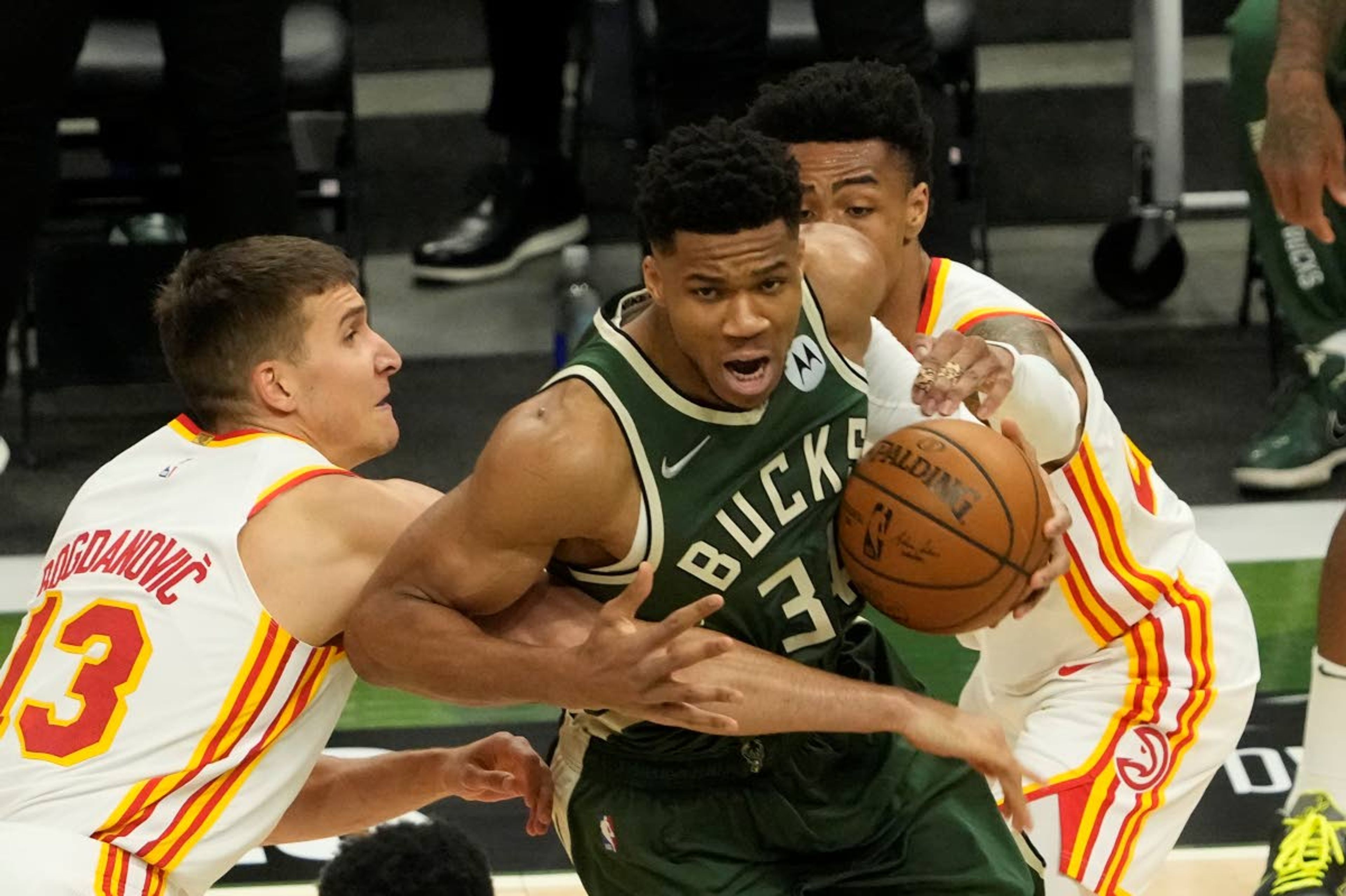 Milwaukee Bucks' Giannis Antetokounmpo tries to get past Atlanta Hawks' Bogdan Bogdanovic (13) and John Collins during the first half of Game 1 of the NBA Eastern Conference basketball finals game Wednesday, June 23, 2021, in Milwaukee. (AP Photo/Morry Gash)