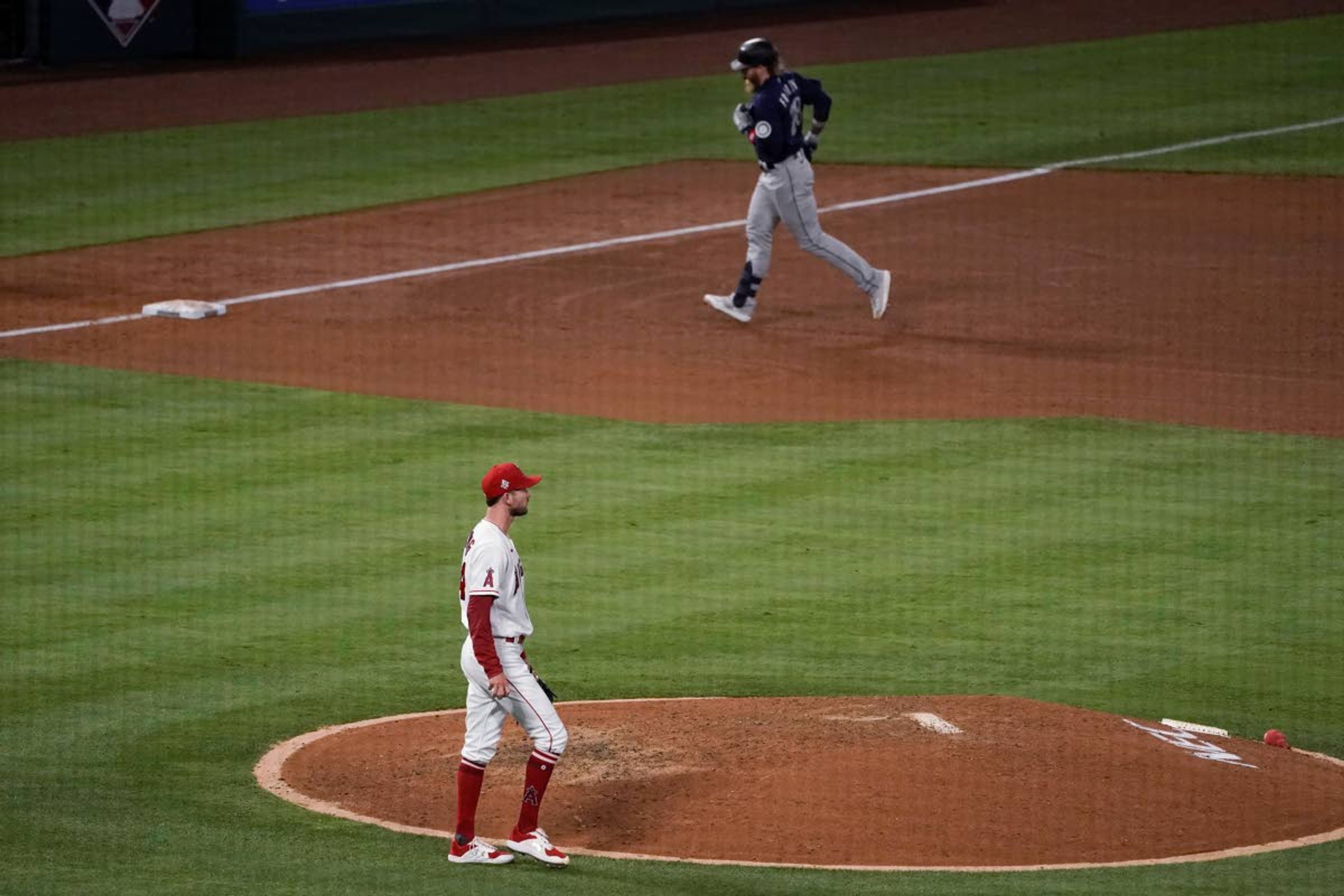 Los Angeles Angels starting pitcher Griffin Canning, bottom, walks around the mound after allowing a three-run home run to Seattle Mariners' Jake Fraley, top, during the fourth inning of a baseball game in Anaheim, Calif., Thursday, June 3, 2021. (AP Photo/Jae C. Hong)