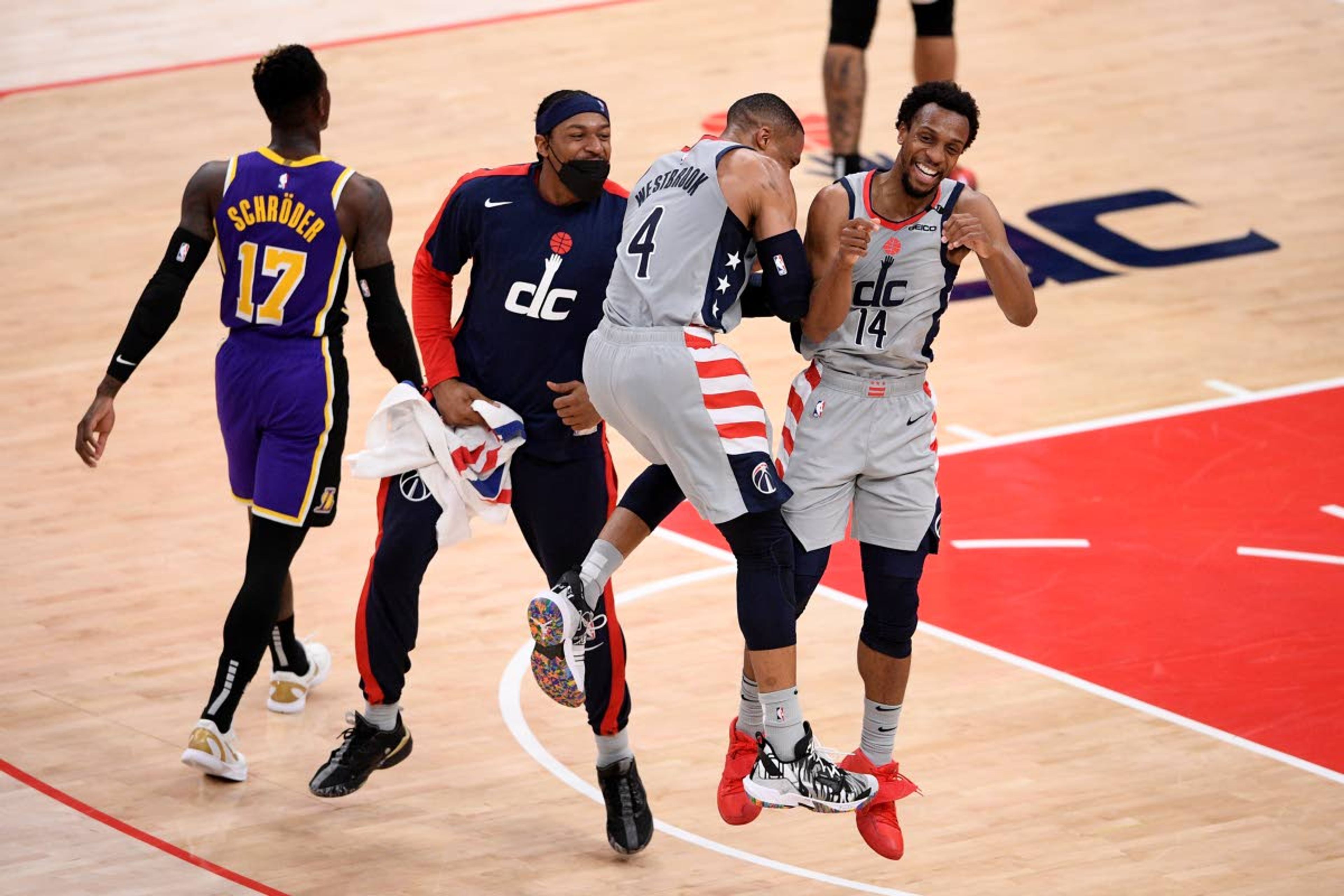 Washington Wizards guard Ish Smith (14) celebrates after his dunk with guard Russell Westbrook (4) and guard Bradley Beal, second from left, during the second half of an NBA basketball game as Los Angeles Lakers guard Dennis Schroder (17) walks by, Wednesday, April 28, 2021, in Washington. (AP Photo/Nick Wass)