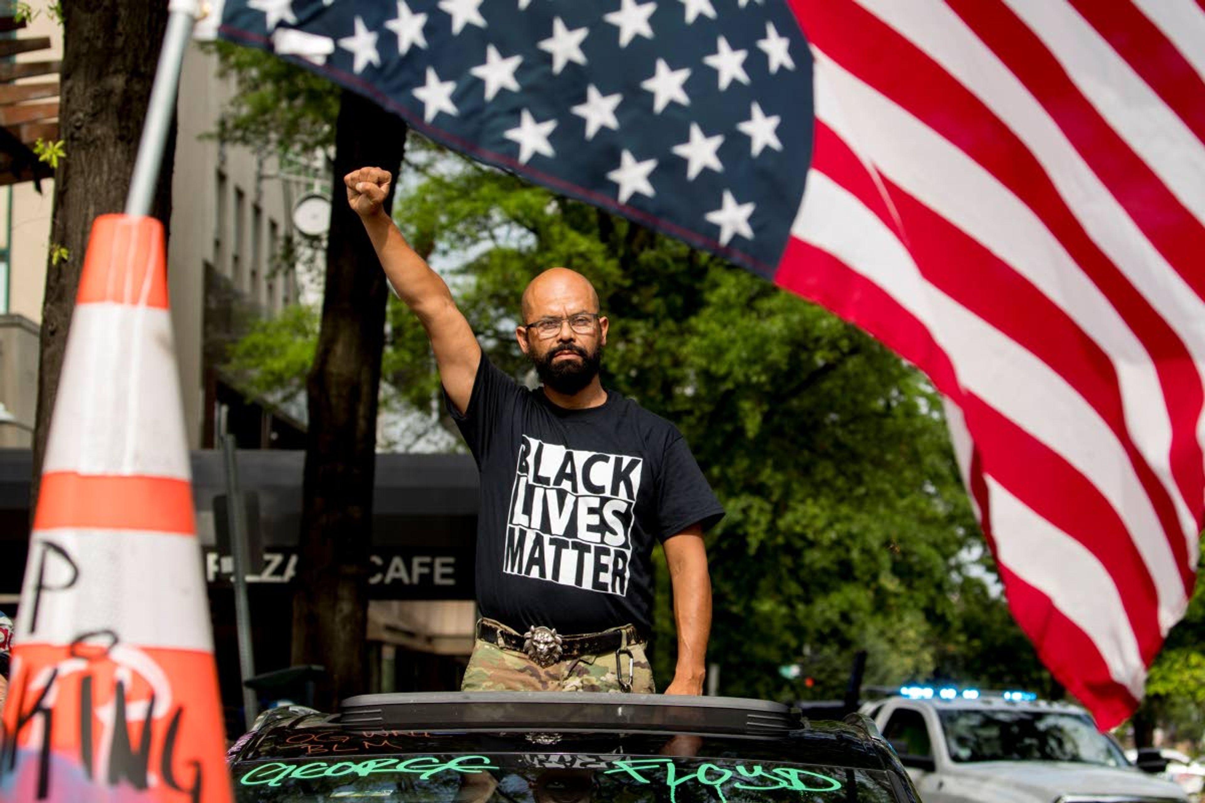 George Floyd’s name is written on the windshield as John Coy wears a shirt that reads Black Lives Matter and stands through his sunroof with his fist in the air at 16th Street Northwest renamed Black Lives Matter Plaza near the White House, Friday, June 19, 2020, in Washington. (AP Photo/Andrew Harnik)