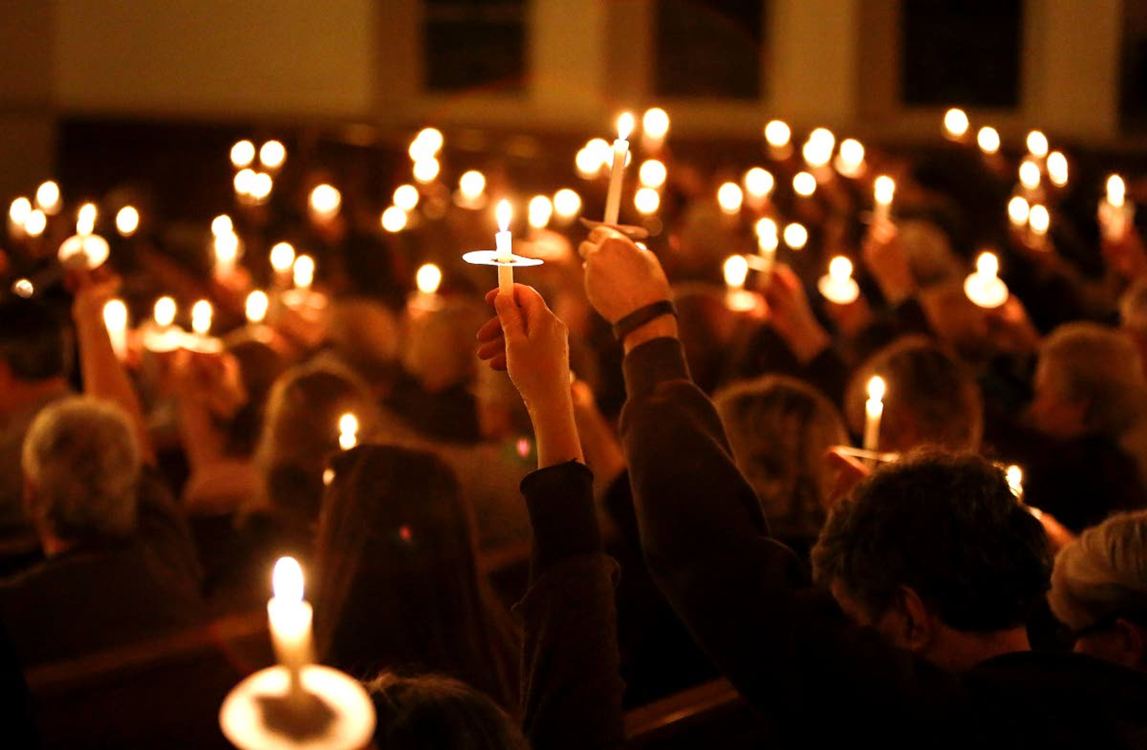 Moscow residents lift candles at First United Methodist Church during a prayer vigil Jan. 11, 2015, to remember the victims of a shooting spree that left three dead and one seriously injured the day prior in Moscow.