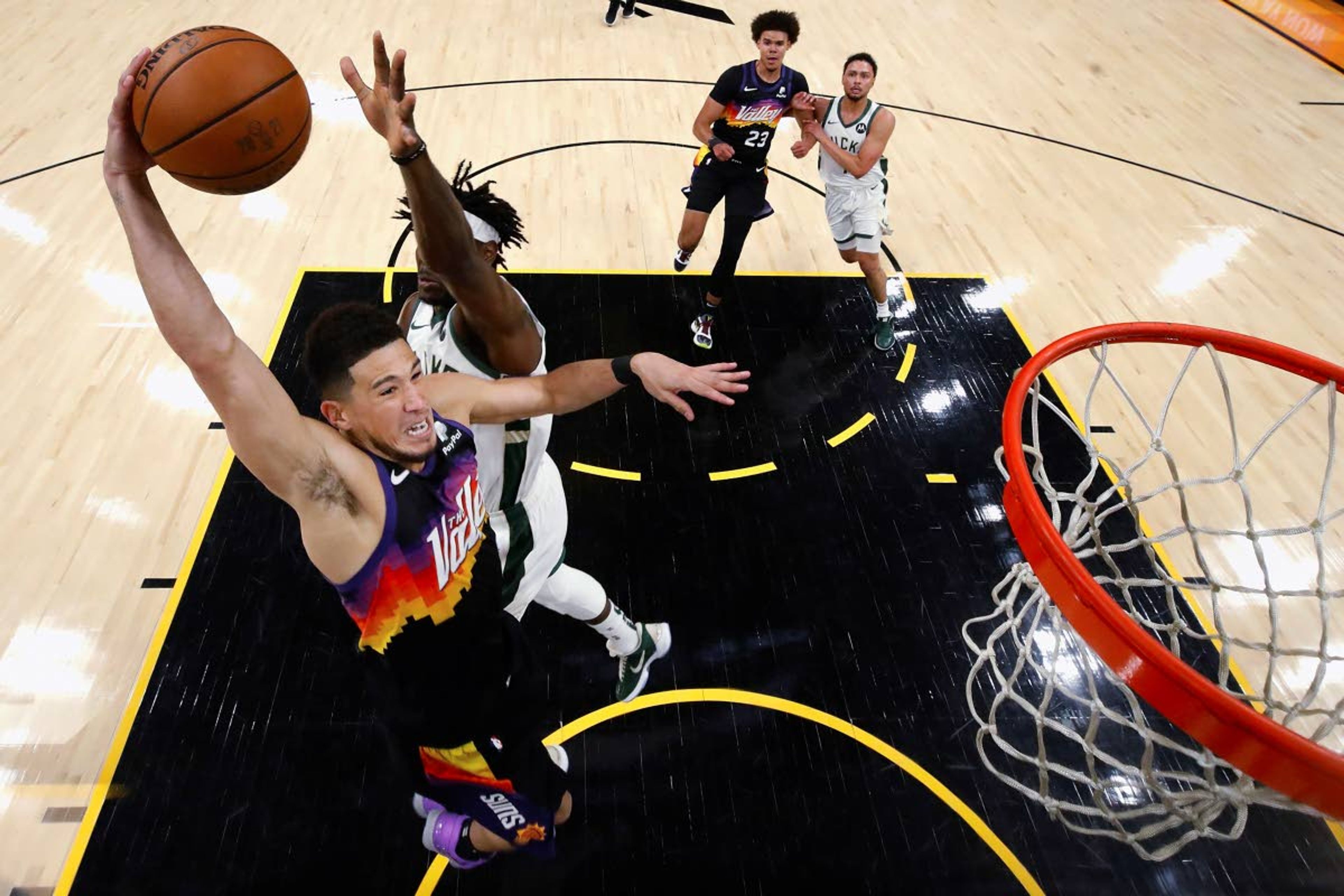 The Suns’ Devin Booker rises up for a dunk against Milwaukee’s Jrue Holiday in the first half of Game 2 of the NBA Finals on Thursday.