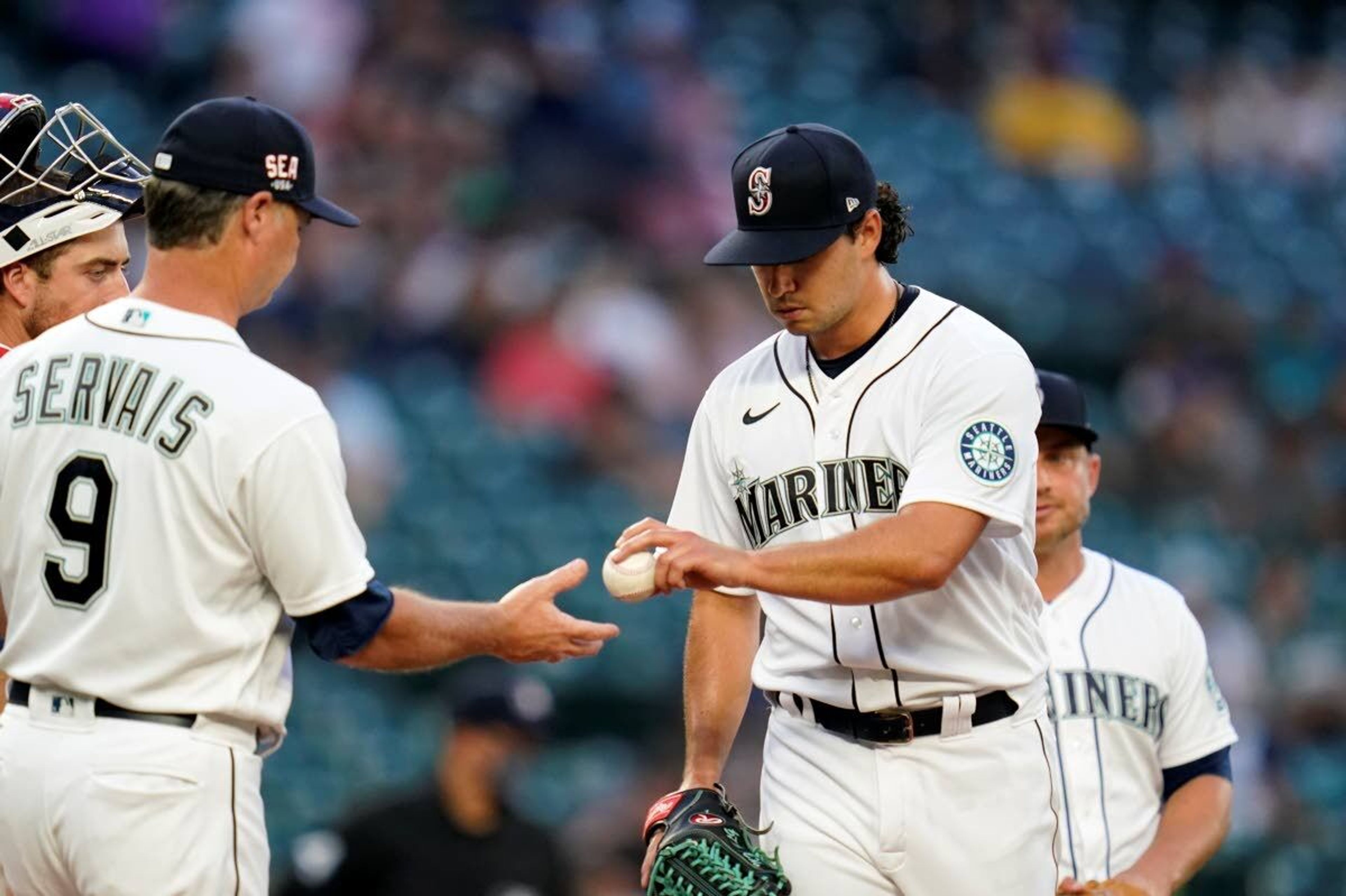 Seattle Mariners starting pitcher Marco Gonzales, right, hands the baseball to manager Scott Servais as he leaves during the fourth inning against the Texas Rangers on Saturday, July 3, 2021, in Seattle. (AP Photo/Elaine Thompson)